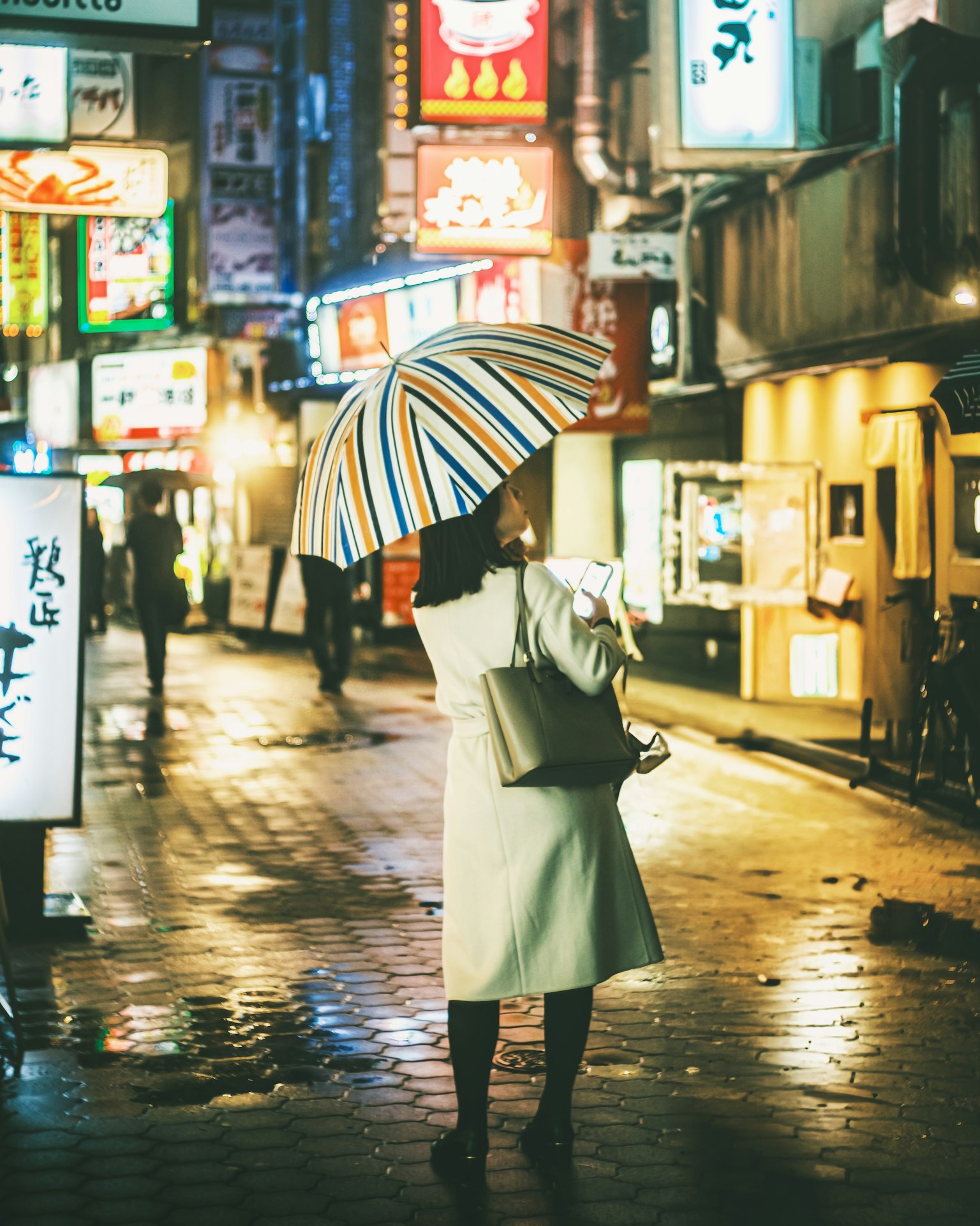 A woman holding an umbrella walking in a rainy street at night