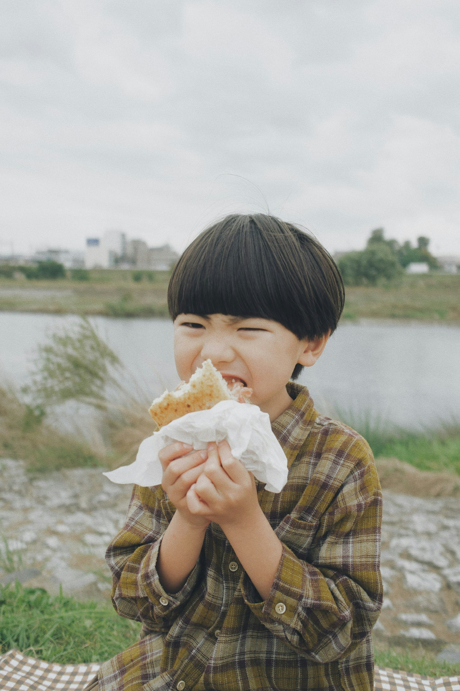 niño sonriente comiendo pan junto al río