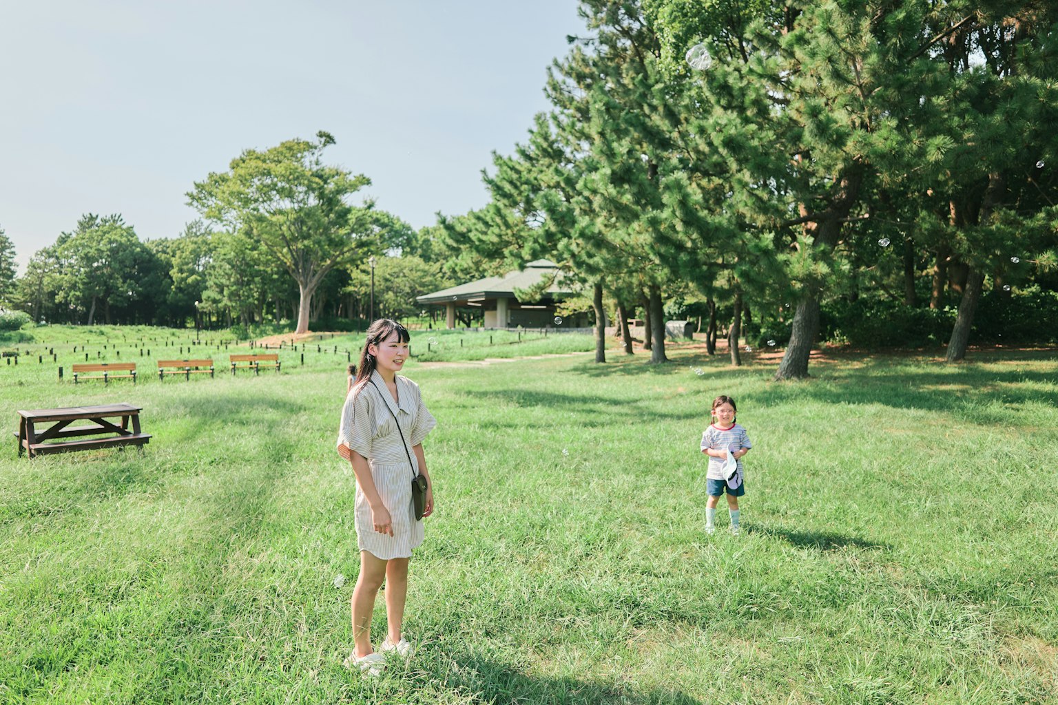 緑の草原に立つ女性と遊ぶ子供の風景