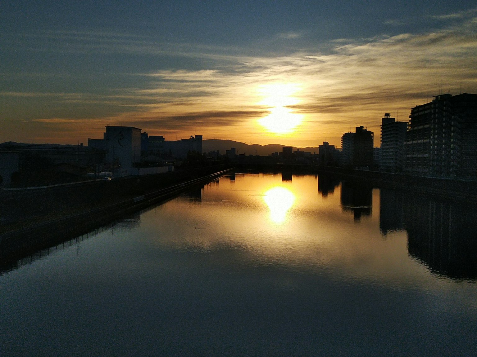 Beautiful sunset reflecting on the river skyline with buildings and calm water