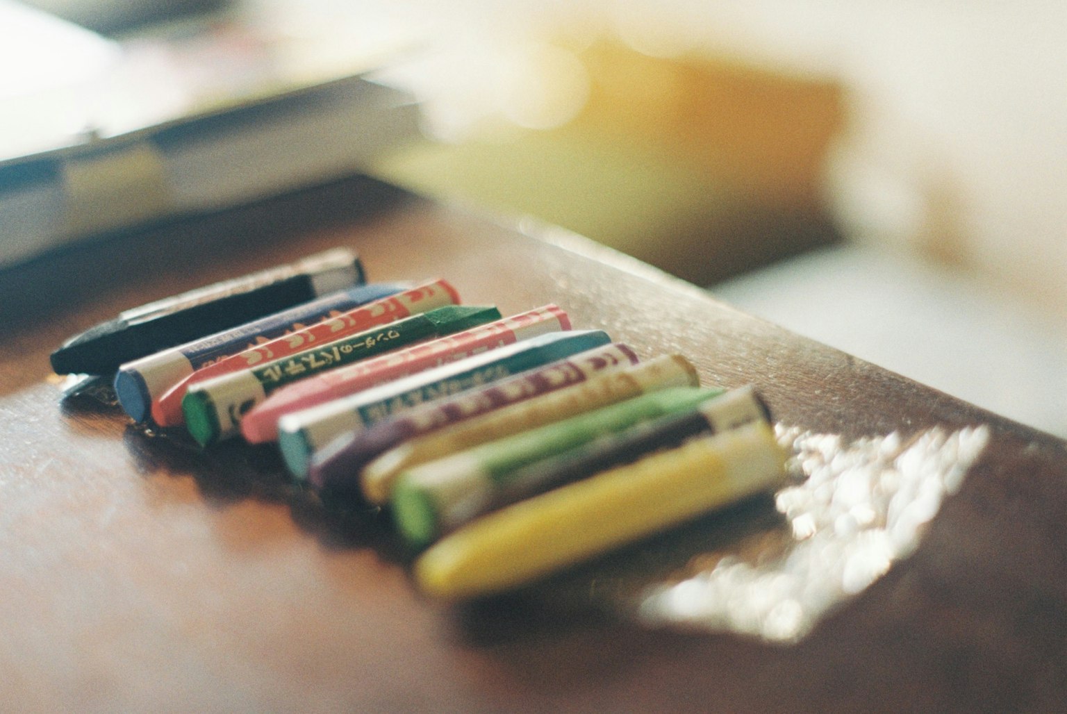 Una fila di pastelli colorati su un tavolo di legno con uno sfondo sfocato