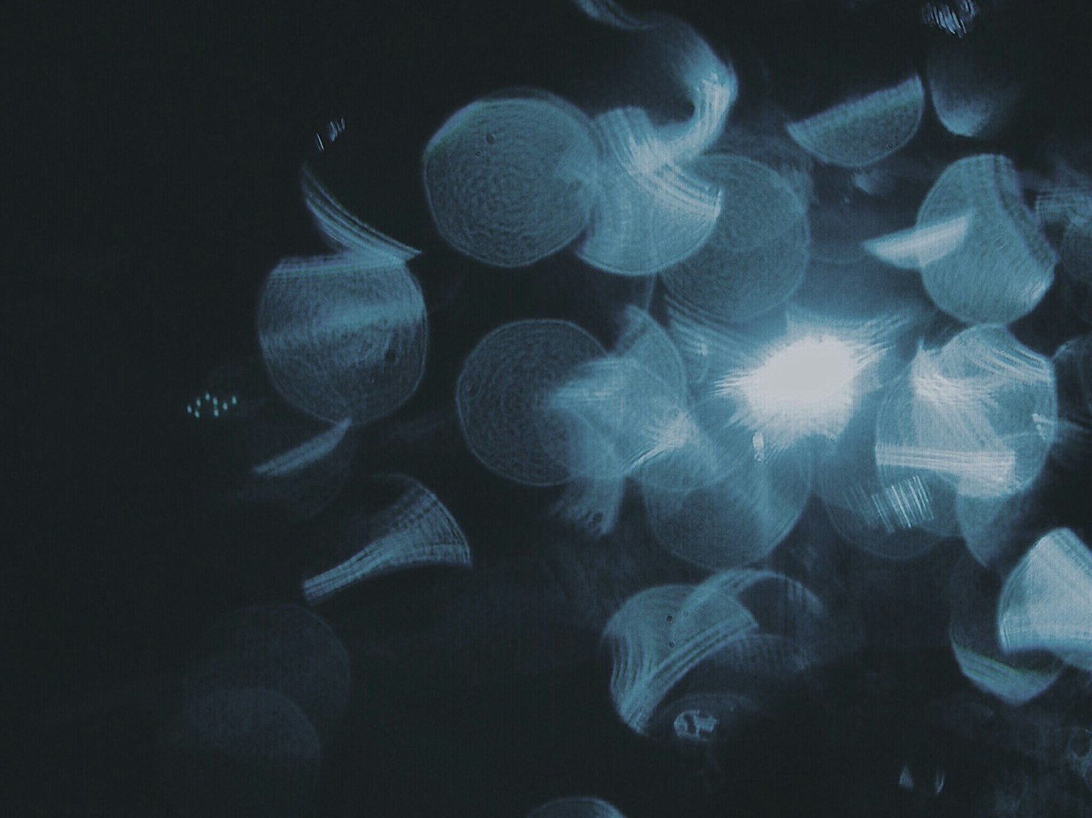 ภาพนามธรรมที่มีวงกลมแสงสีน้ำเงินลอยอยู่บนพื้นหลังมืด