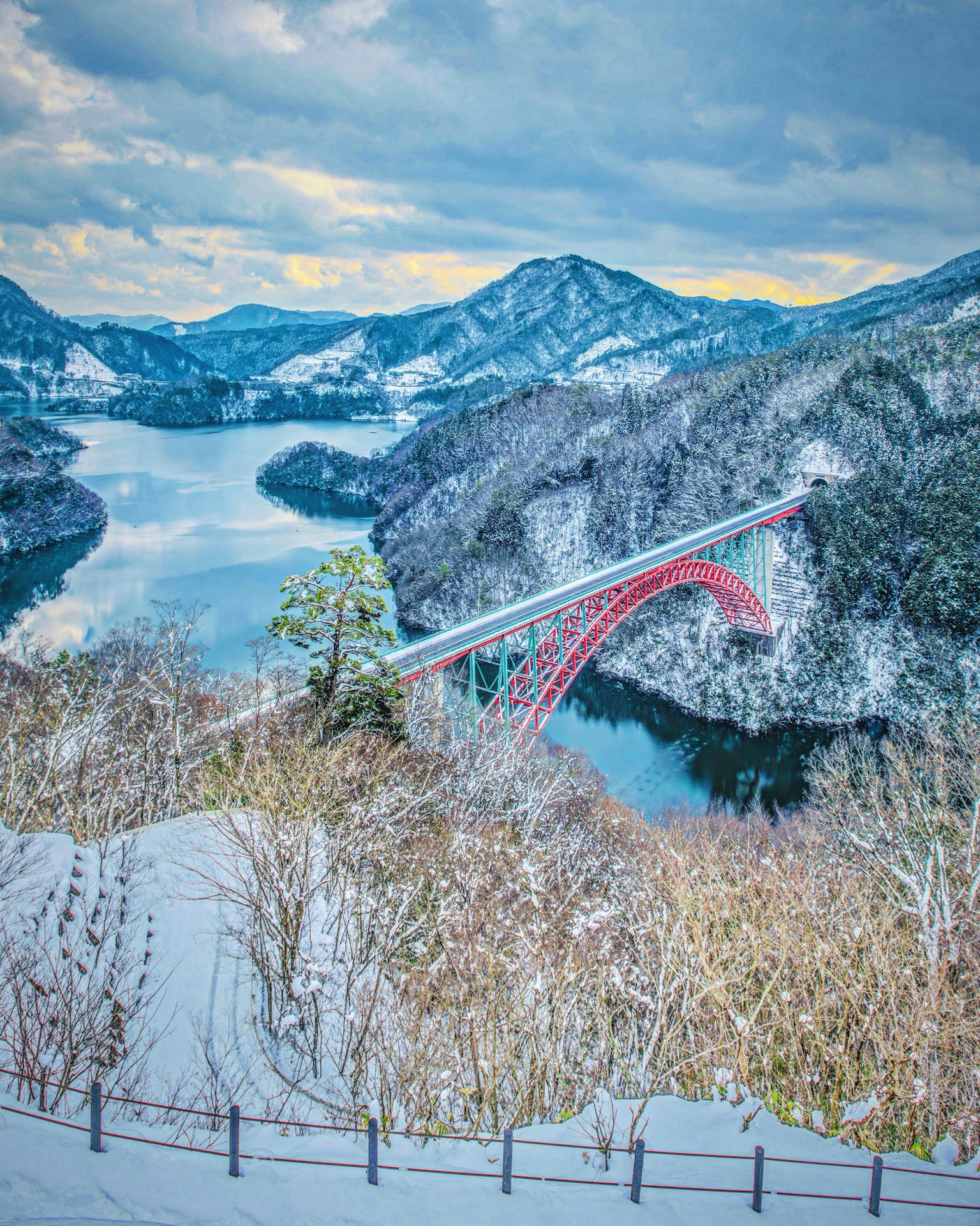 雪山和湖泊背景下的红色桥梁风景