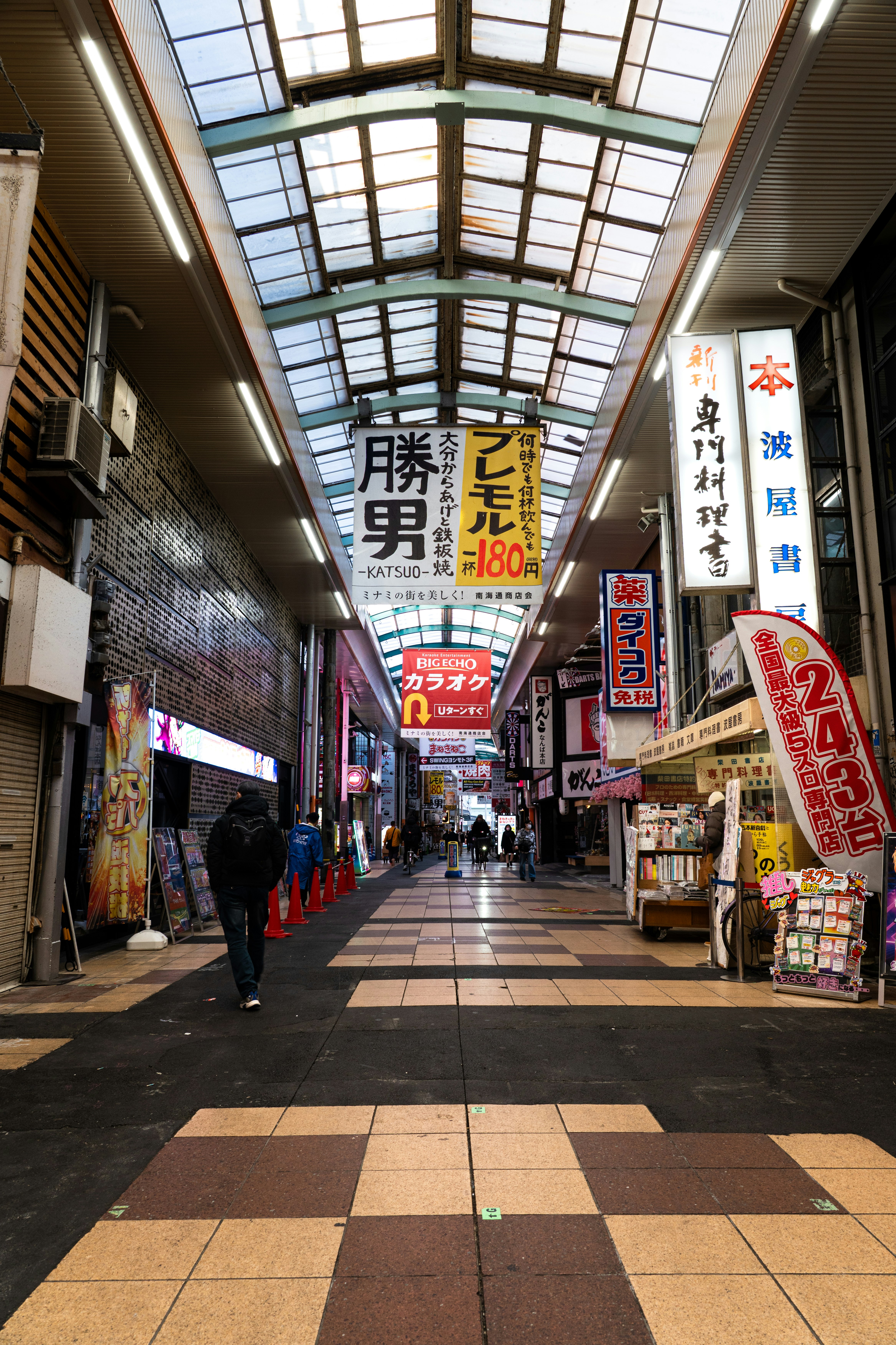 アーケード商店街の通路に掲げられた看板と人の流れ