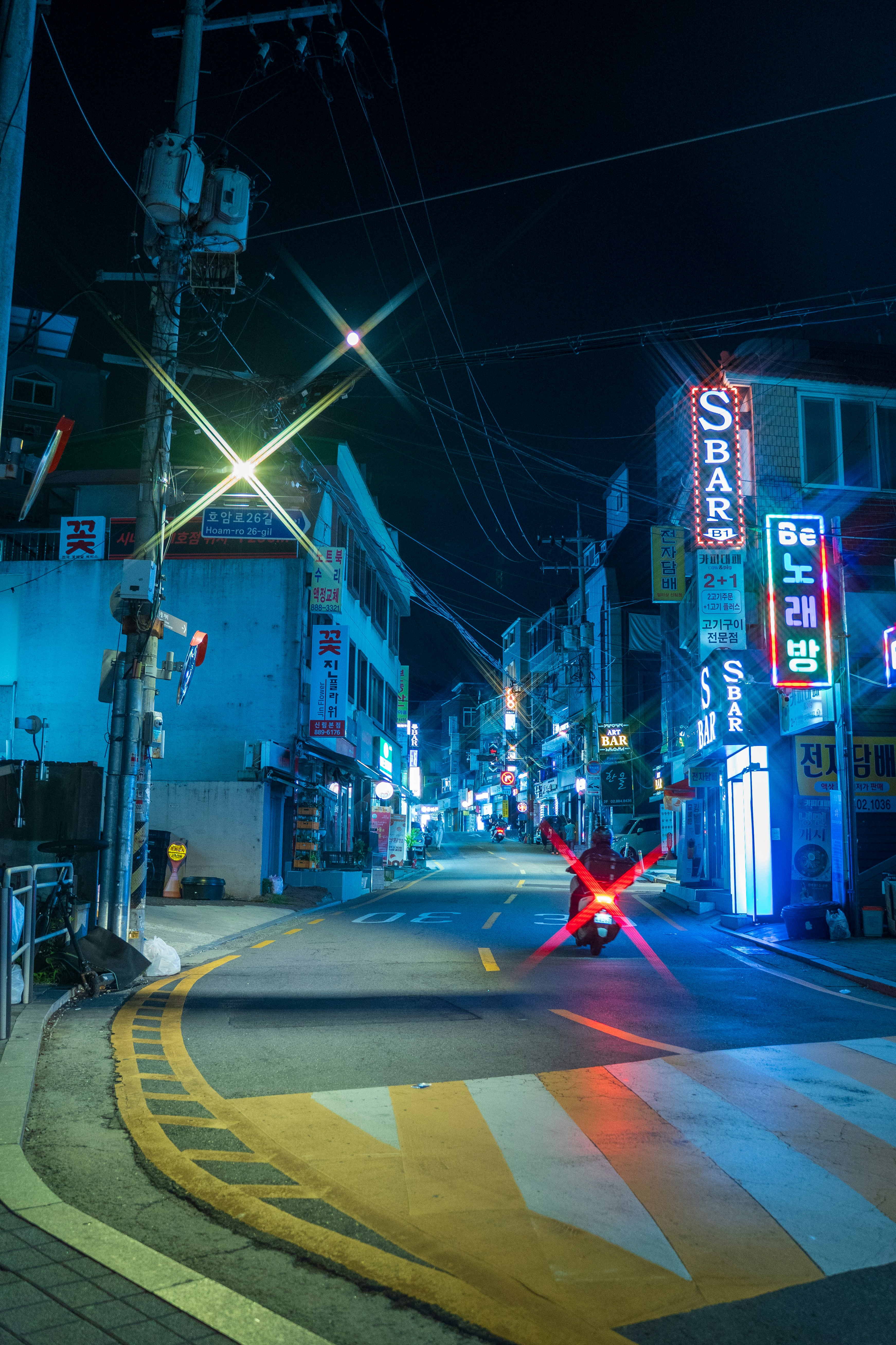 夜の路地に並ぶ電柱と看板のある交差点