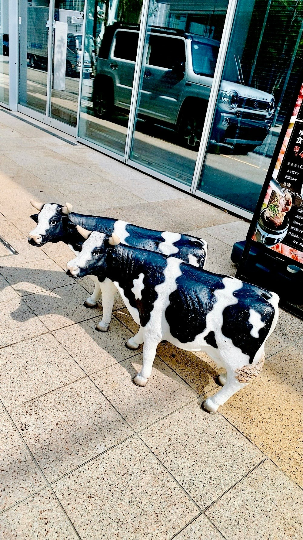 焼肉屋の前にいる牛の置物と子犬のような犬の群れ