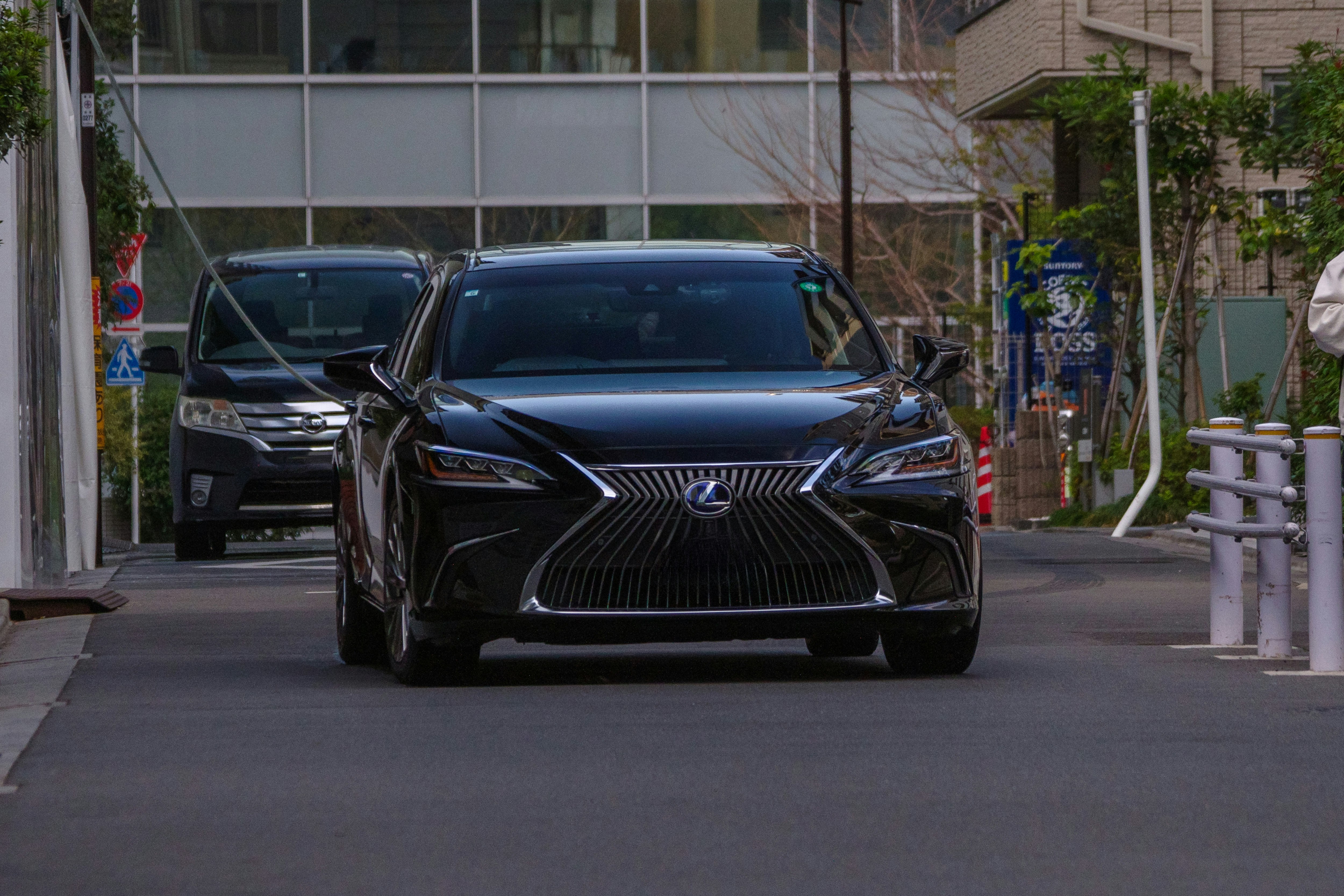 LEXUS/TOYOTAのロゴが見える黒い高級車が路上に並ぶ街並み