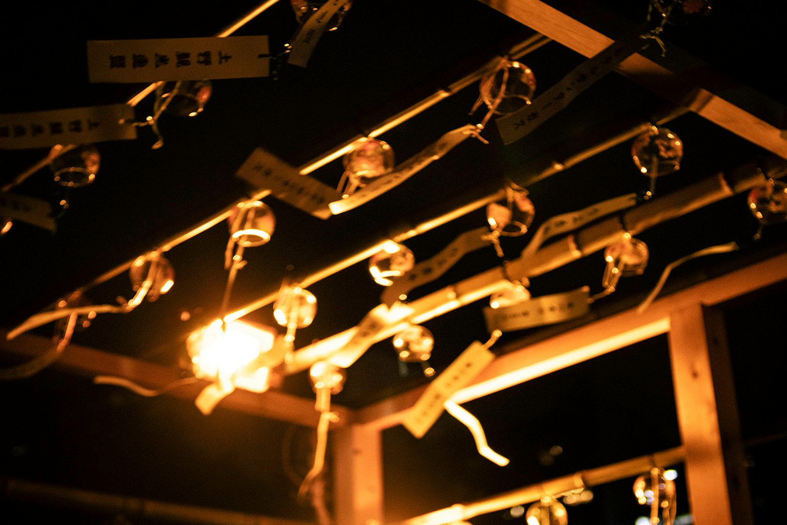 夜の中で光る鈴とおみくじの飾りがある神社の風景