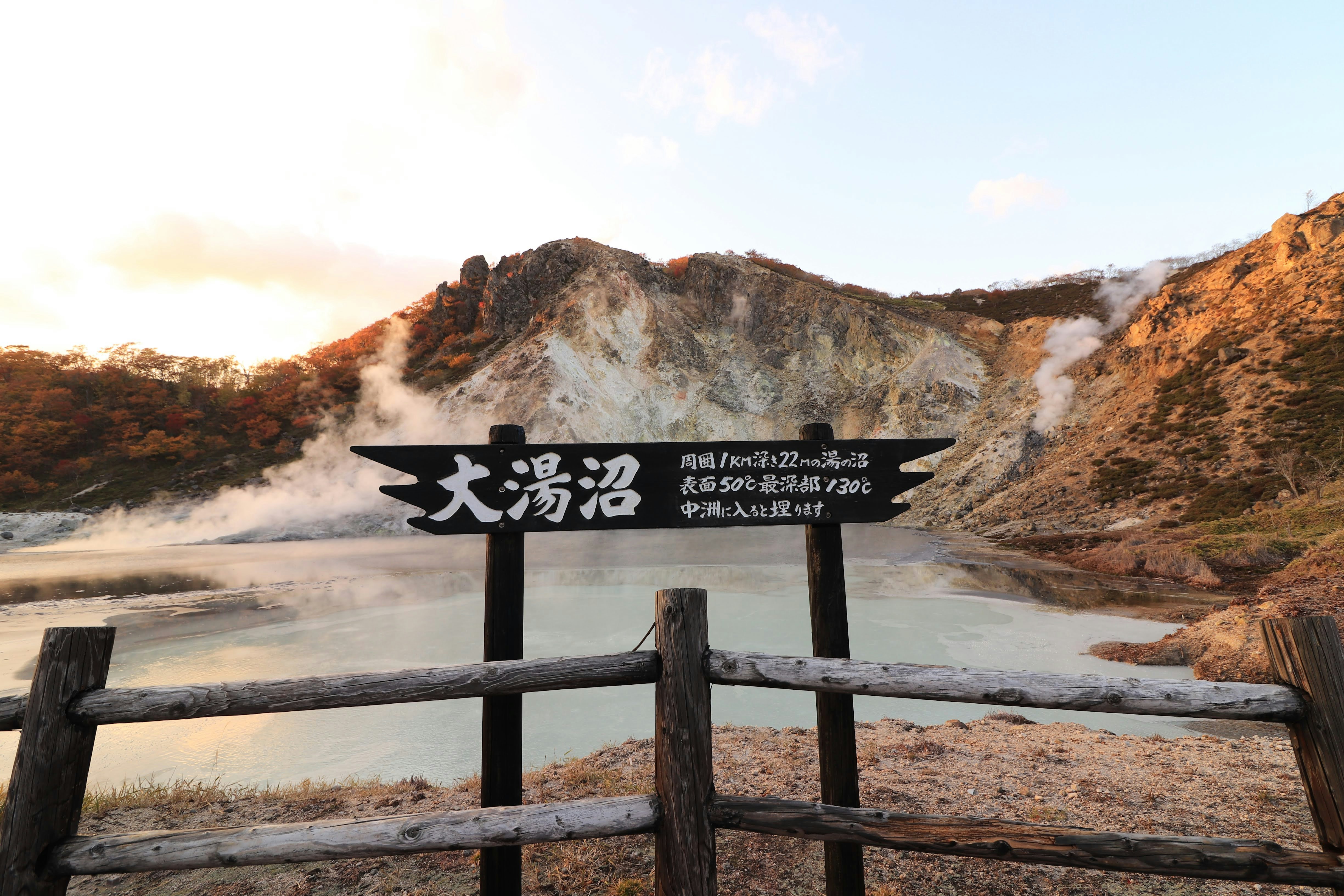 荒涼溫泉地的指示牌與岩石山丘景觀