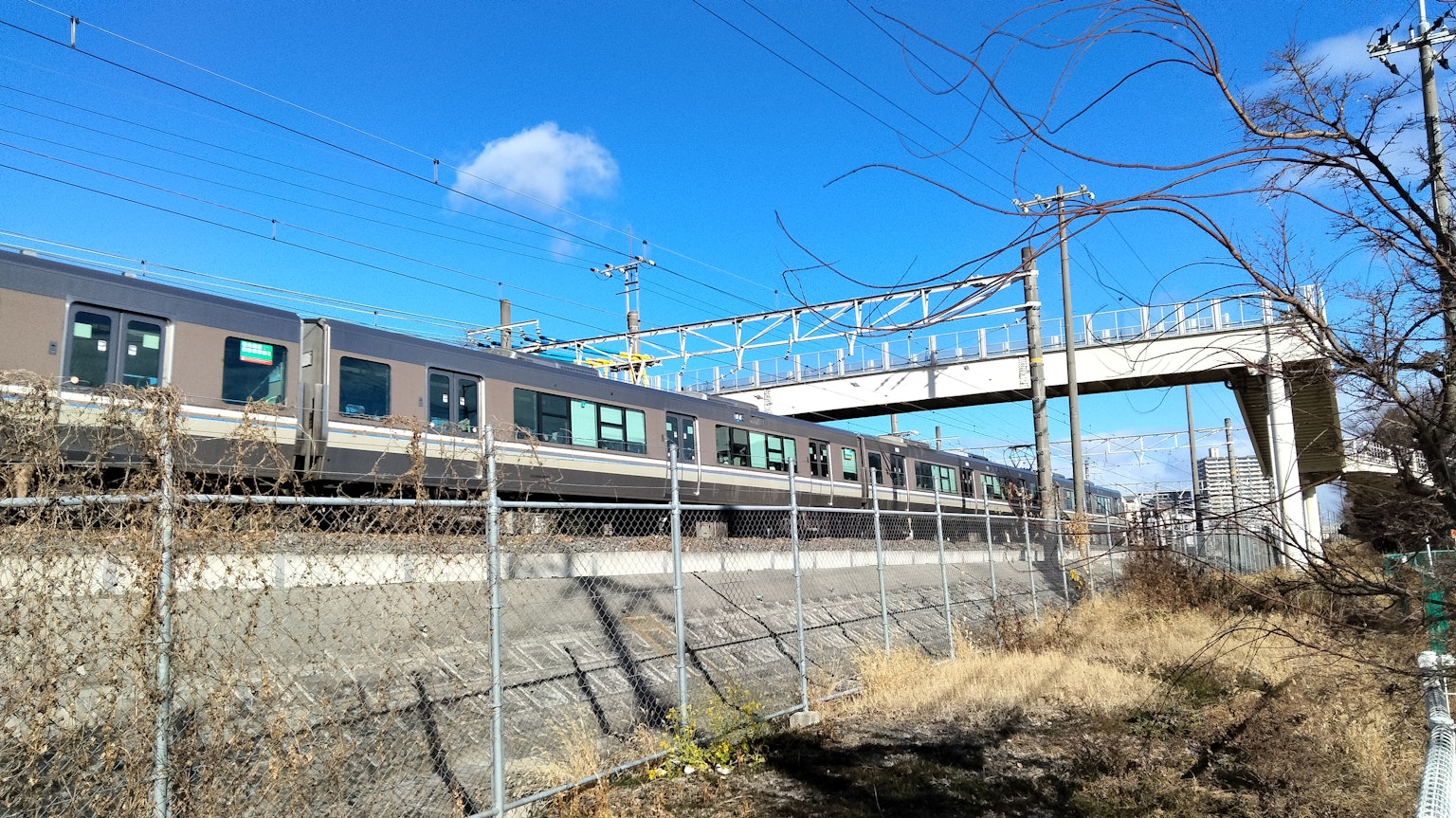 Train passing under a bridge with a clear blue sky