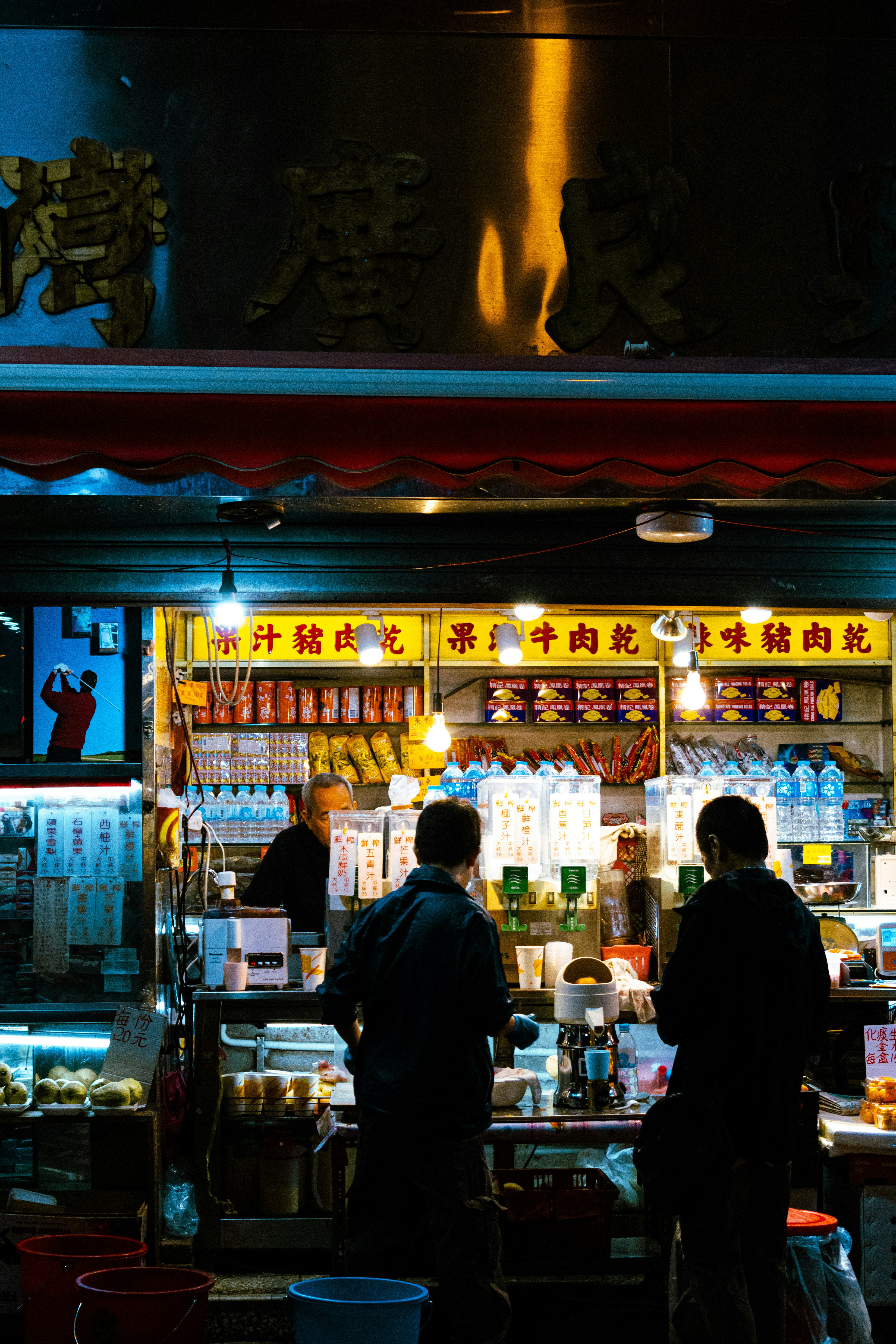 香港の夜の市場で屋台の看板が並ぶ通りの風景