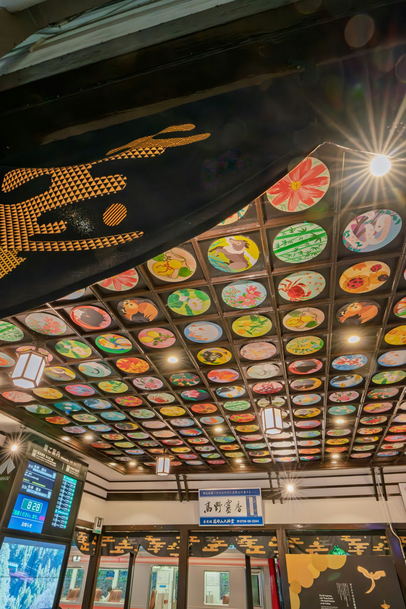 極楽橋駅の天井に並ぶカラフルな絵皿と提灯のある店内