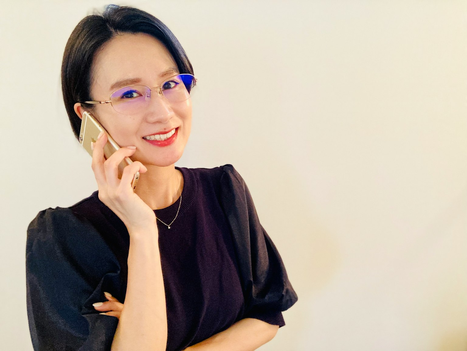 Wanita berpakaian hitam tersenyum saat berbicara di telepon