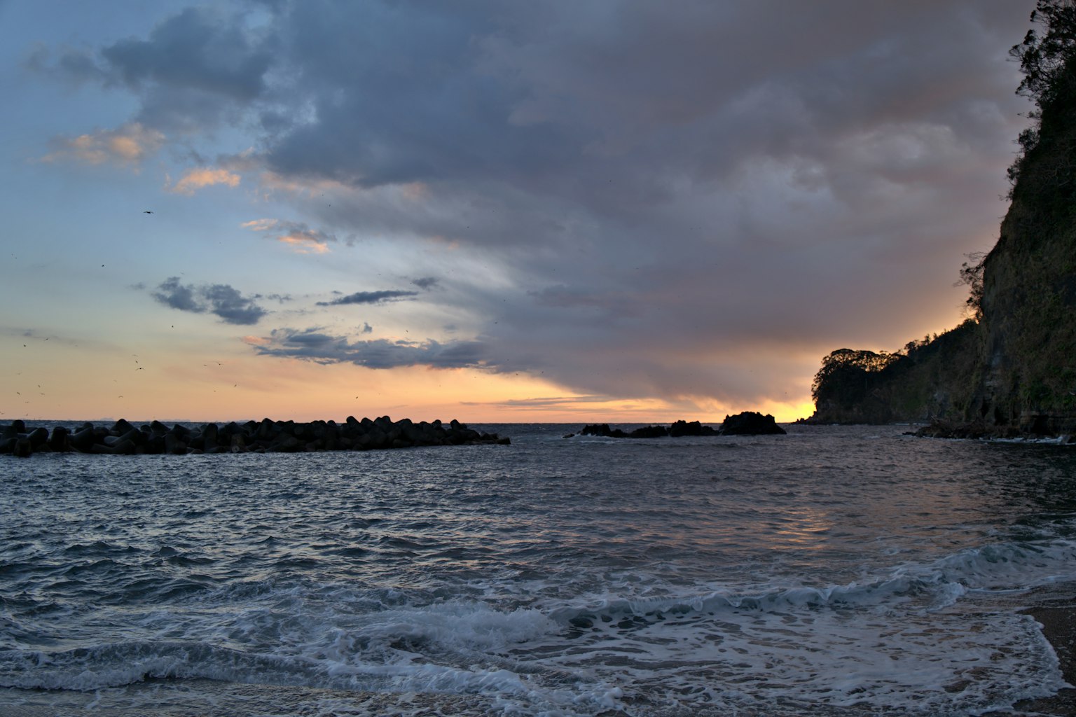 Coastal sunset view with waves and rocky shoreline