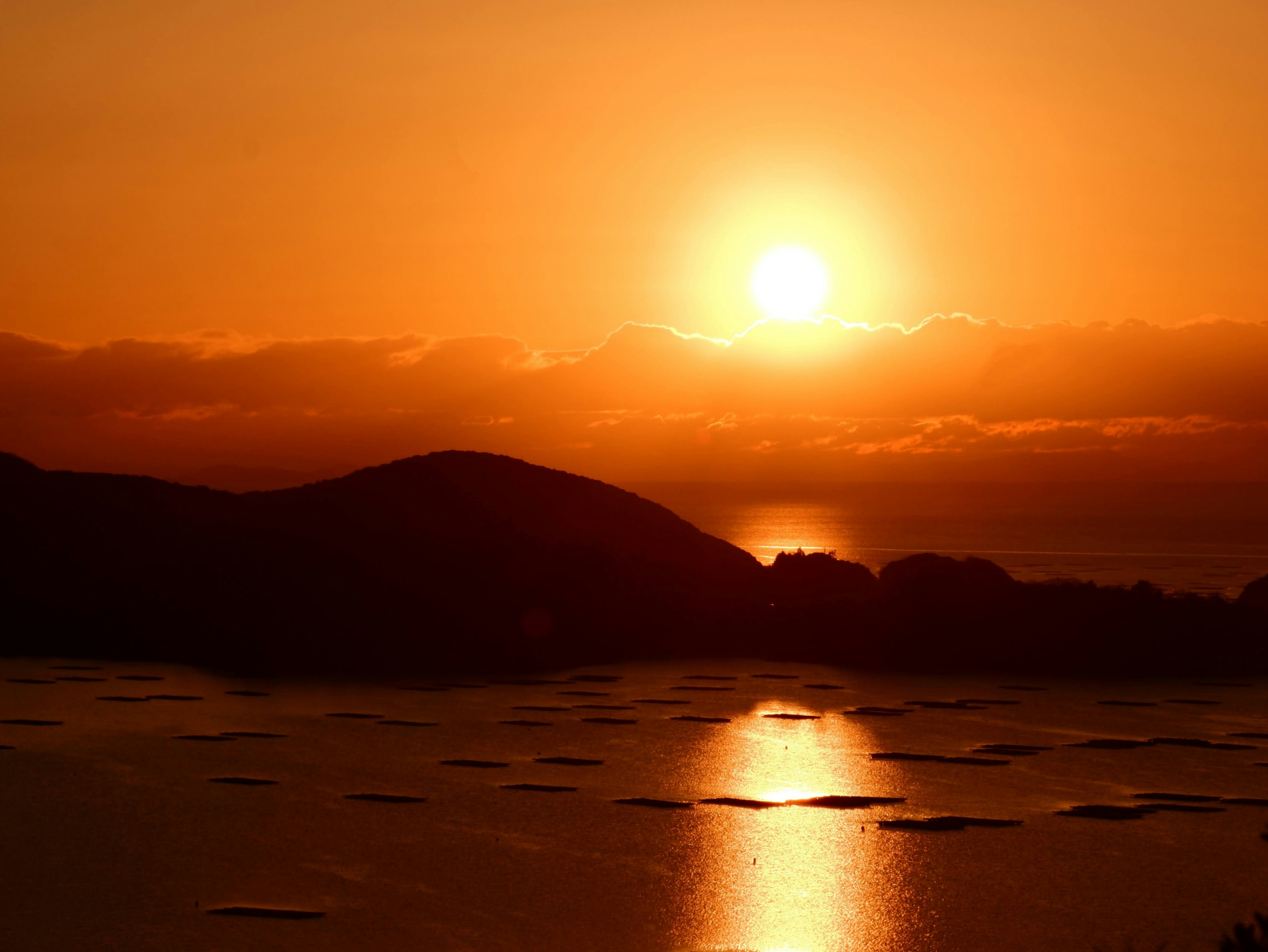 日の出の光が海面に伸びる夕景の風景