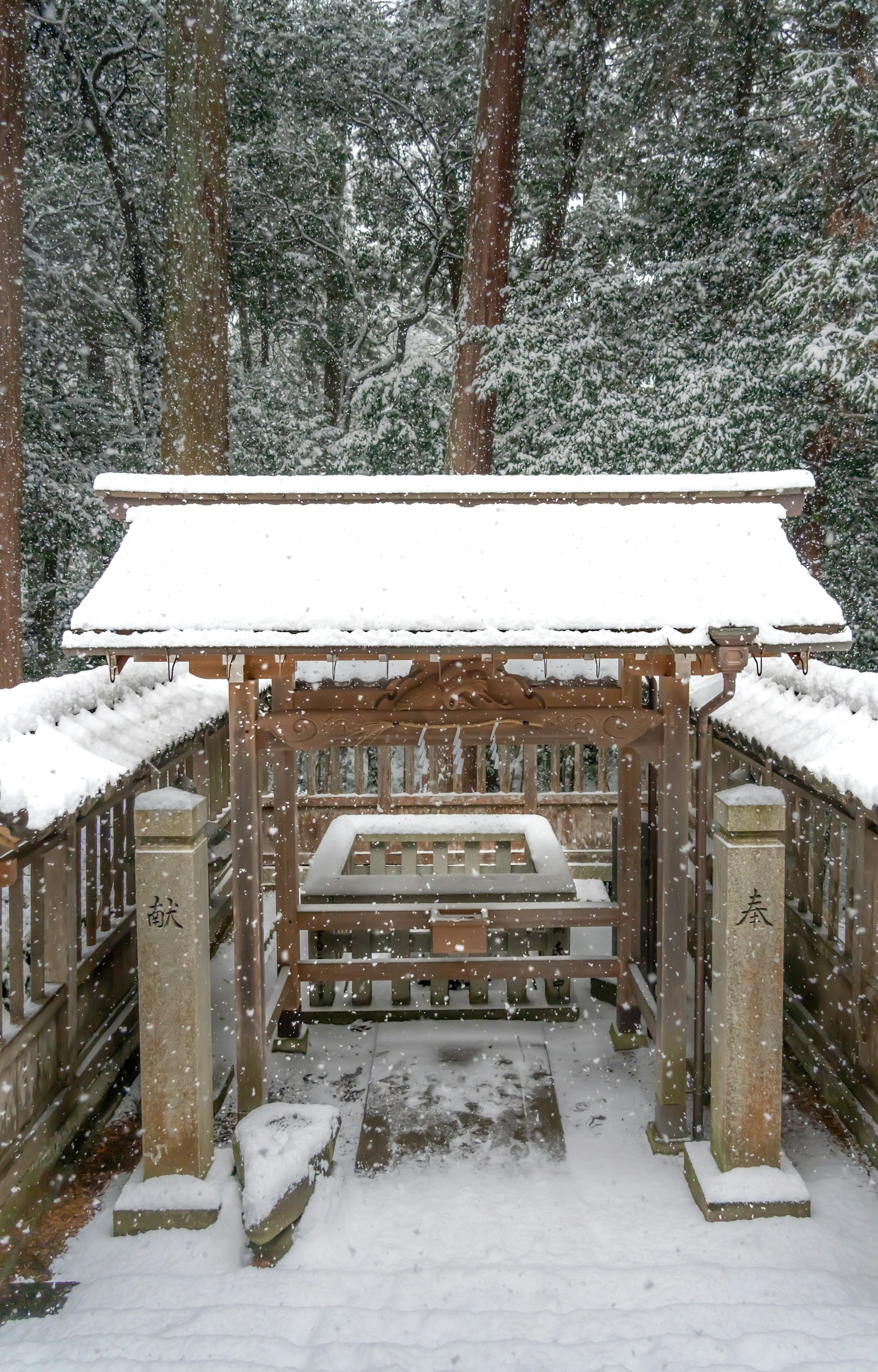 A snow-covered shrine entrance with stone pillars and wooden structure