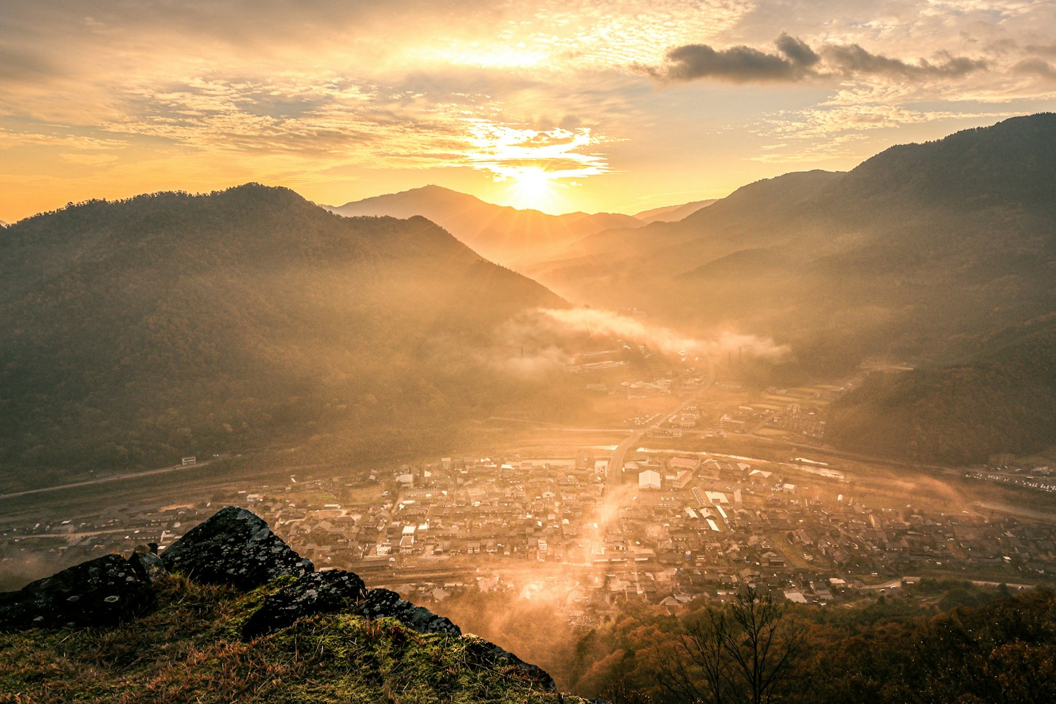 Tramonto sulle montagne nebbiose e sulla valle