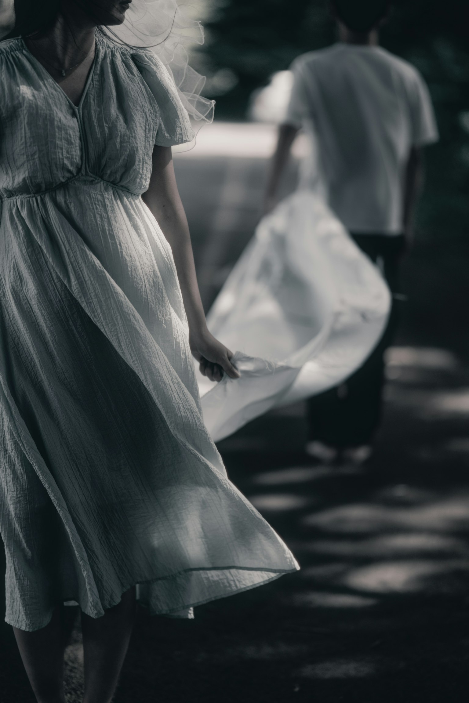 薄暗い道を歩く白いドレスの女性と後ろの男性