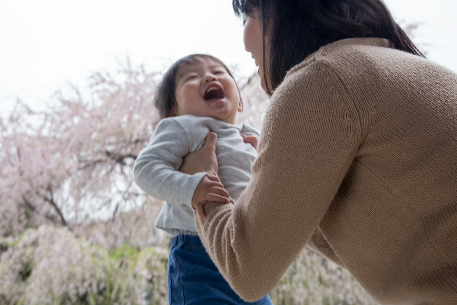 Fröhlicher Moment zwischen einer Mutter und ihrem Kind vor Kirschblütenbäumen