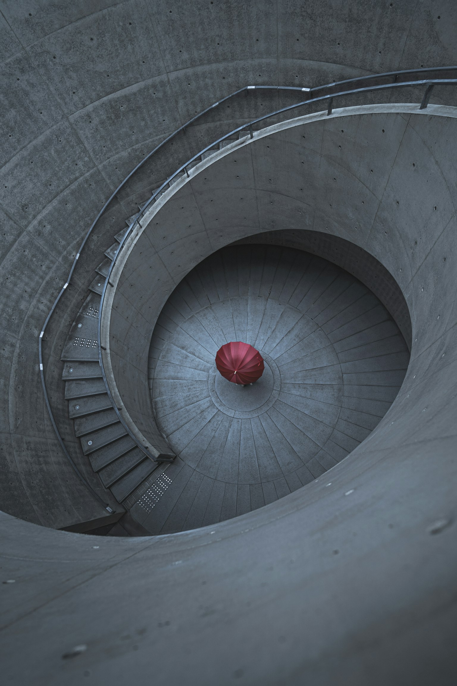 Escalera de concreto en espiral con una esfera roja en el centro