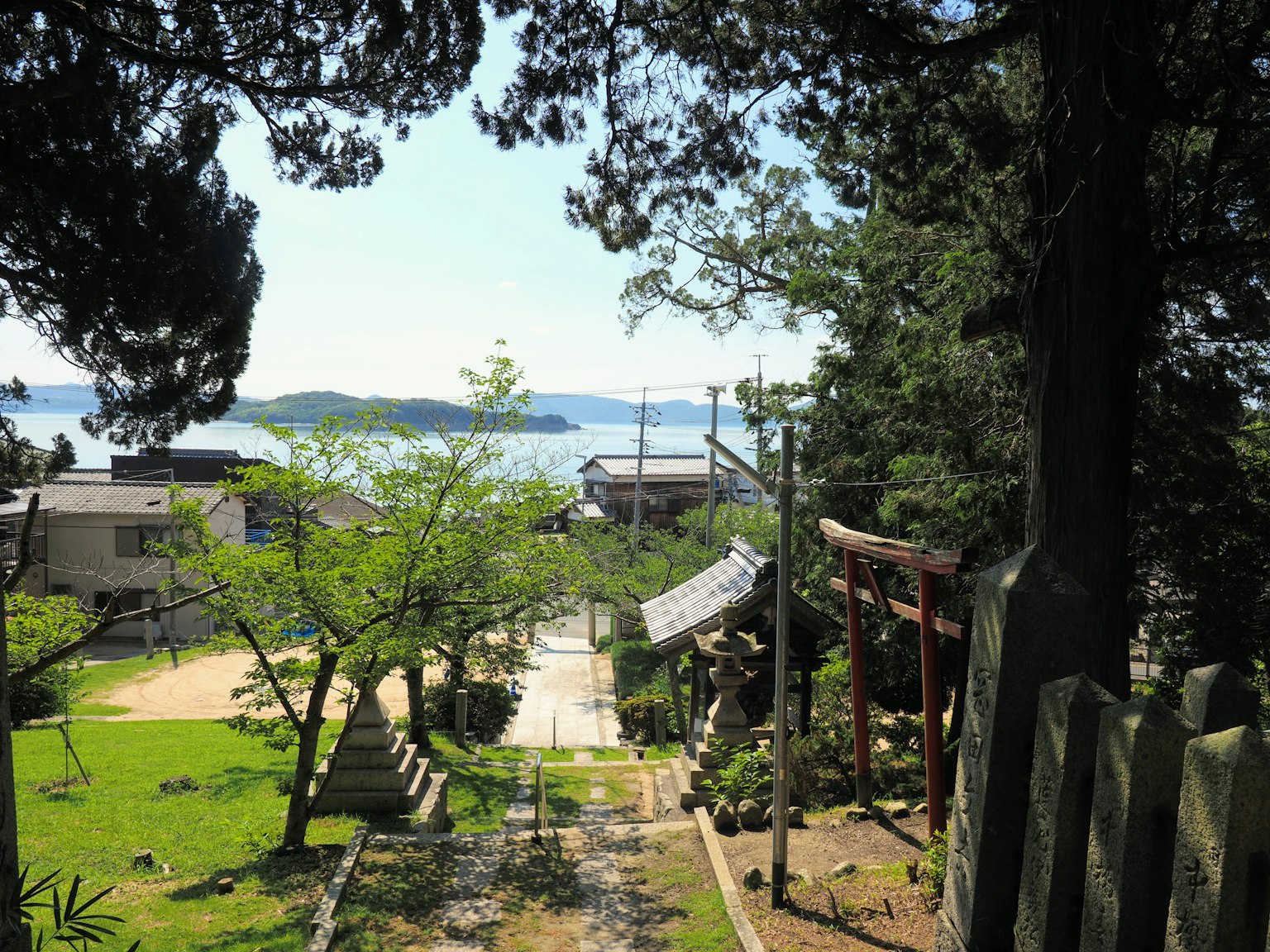 Malersicher Blick auf einen Schrein mit einem Weg, der zum Meer führt, umgeben von Grün
