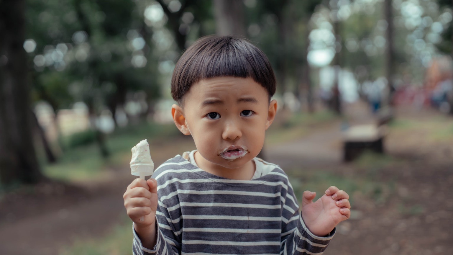 Trẻ em cầm kem trong công viên với biểu cảm ngạc nhiên