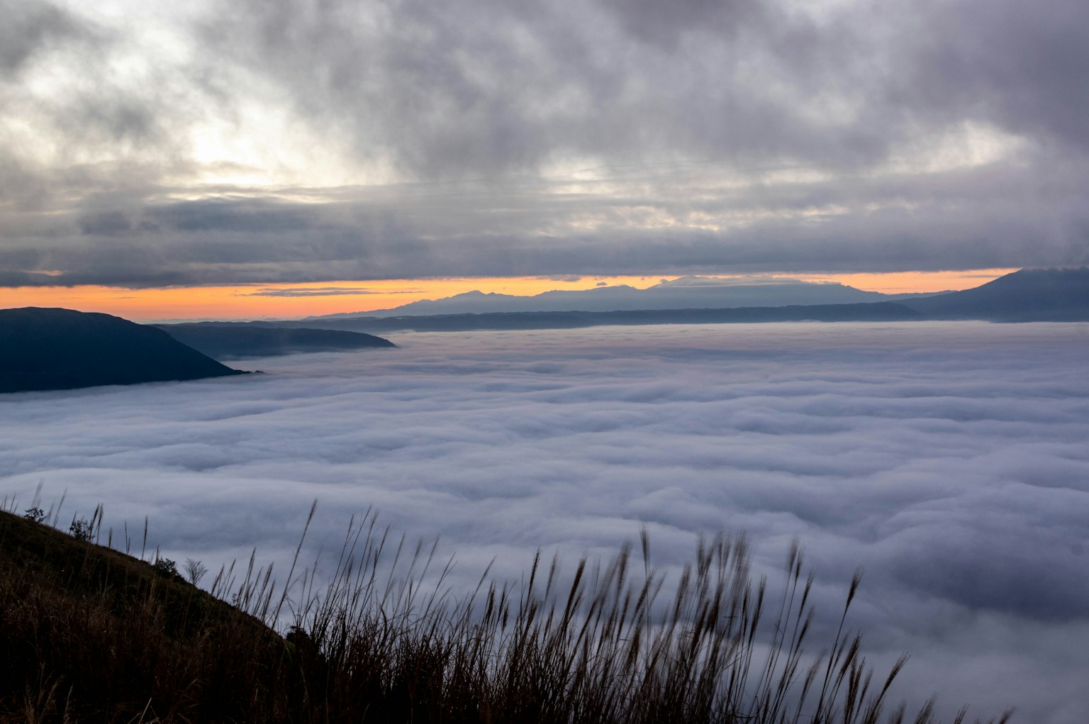 A breathtaking view of a sea of clouds at sunset with distant mountains