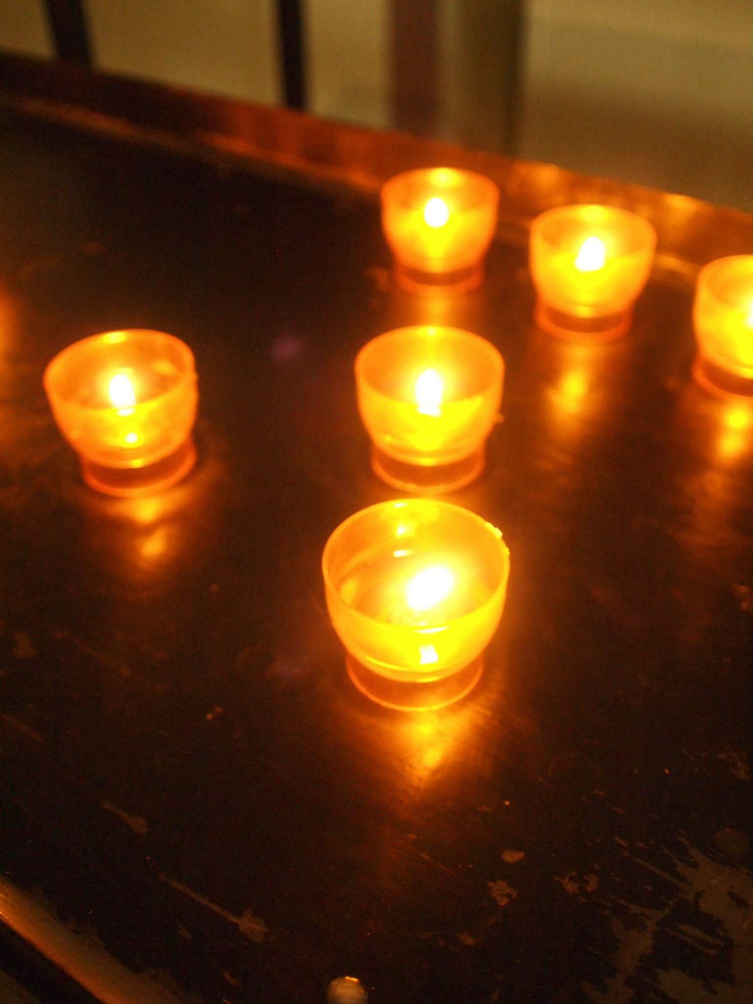 Kleine Kerzen, die orangefarbenes Licht abgeben, auf einer Fläche angeordnet