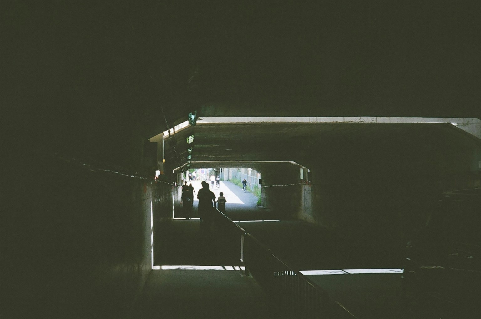 People standing in a dark tunnel with a lighted path ahead