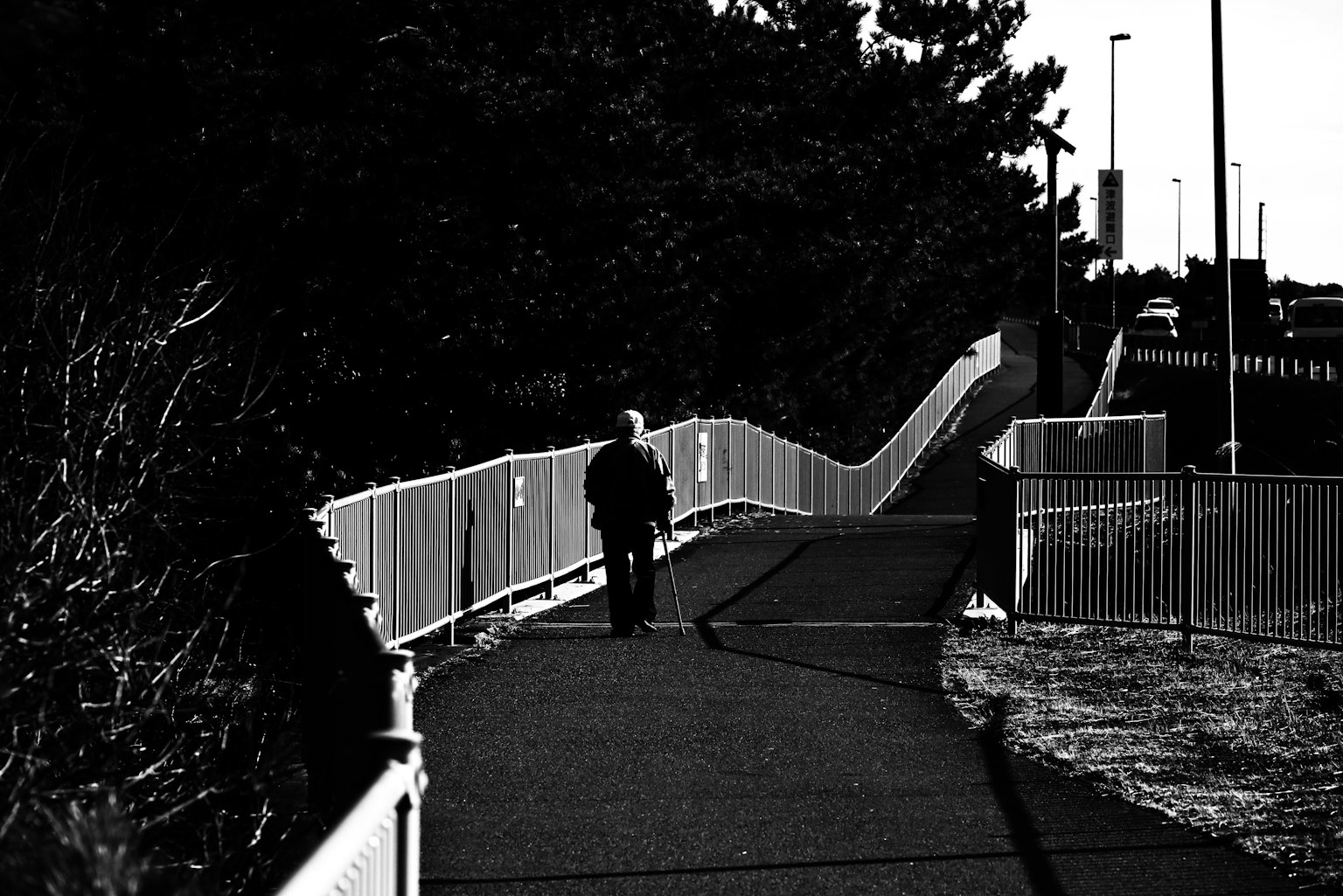 A person walking on a pathway with a white fence