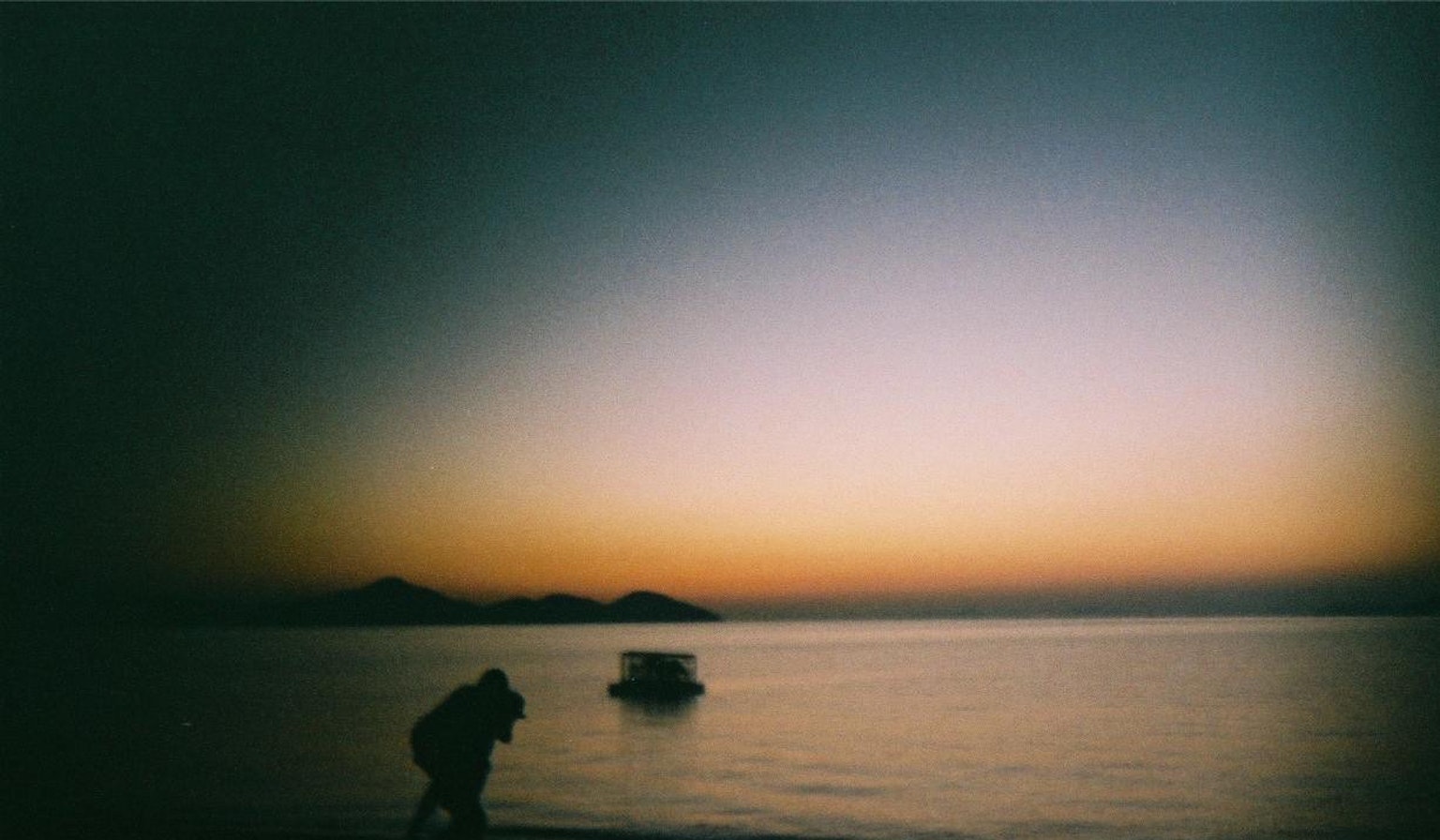 Malerscher Blick auf einen Sonnenuntergang über dem Meer mit der Silhouette eines Bootes