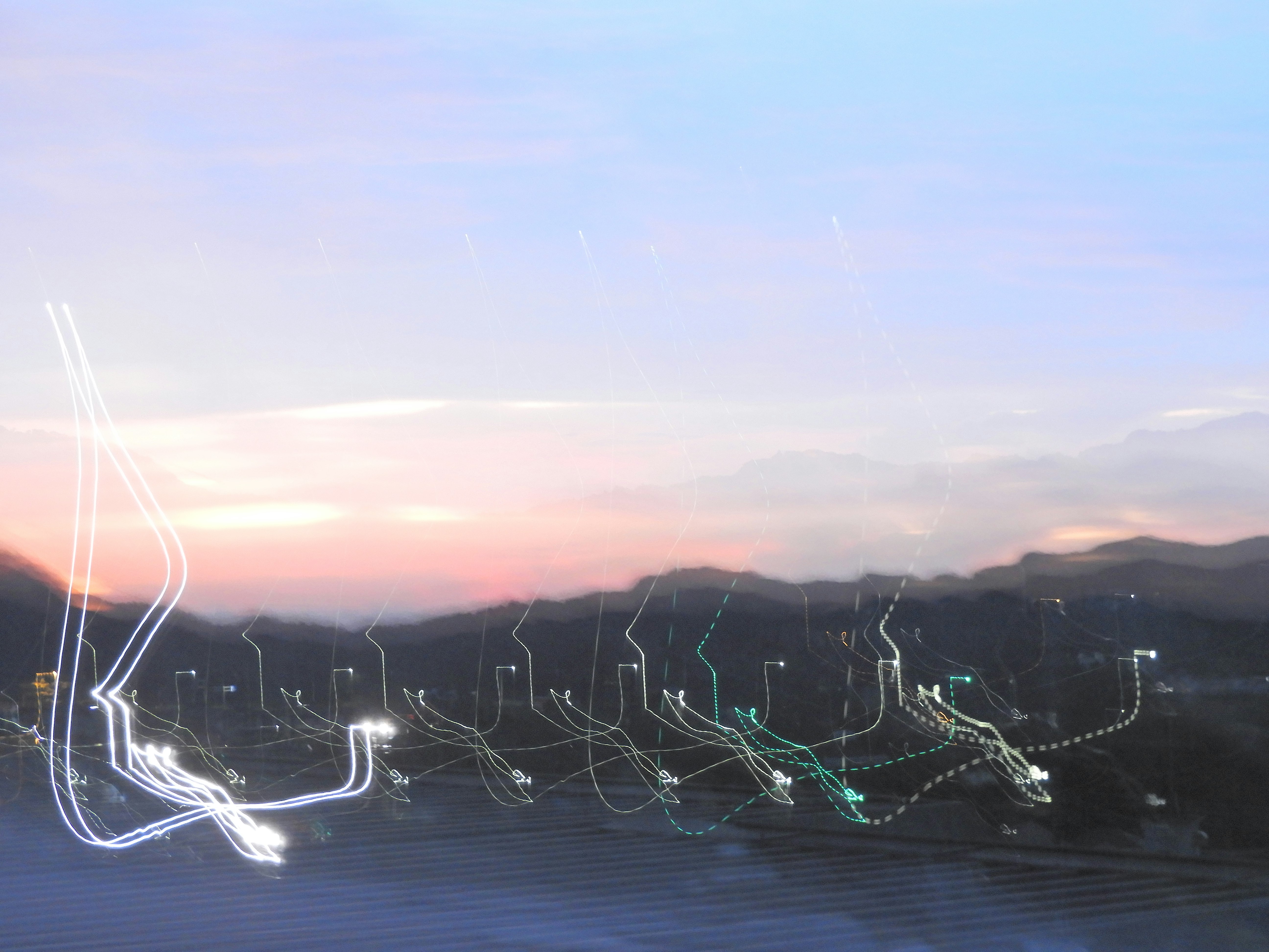 light trails on a highway at night with distant cityscape
