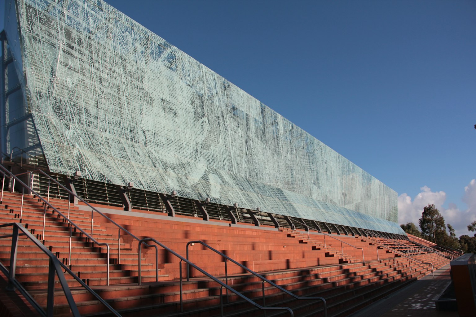 Außenansicht eines Gebäudes mit großem Wandgemälde und roten Treppen