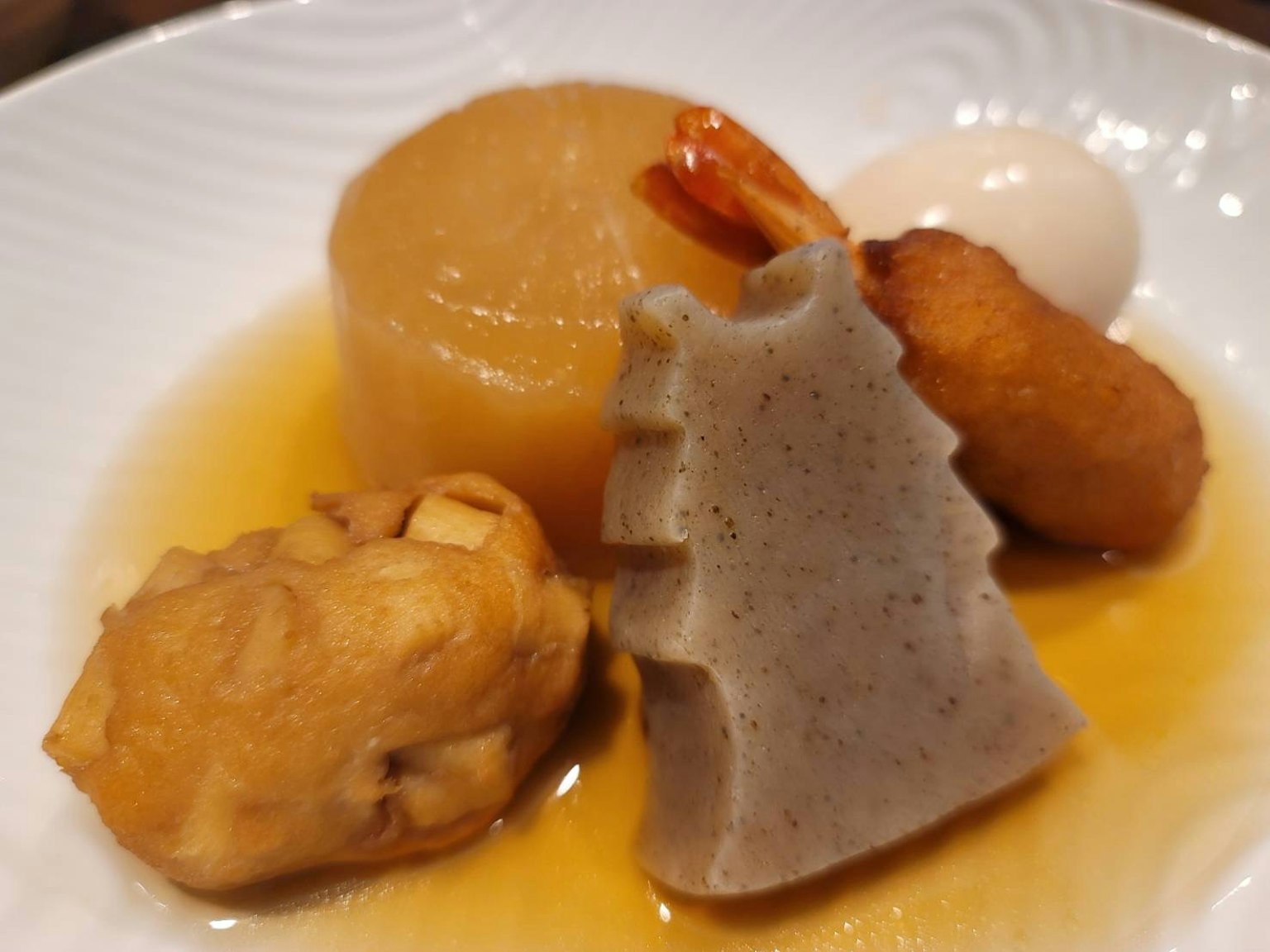 A dish of Japanese cuisine featuring root vegetables shrimp and a soft-boiled egg