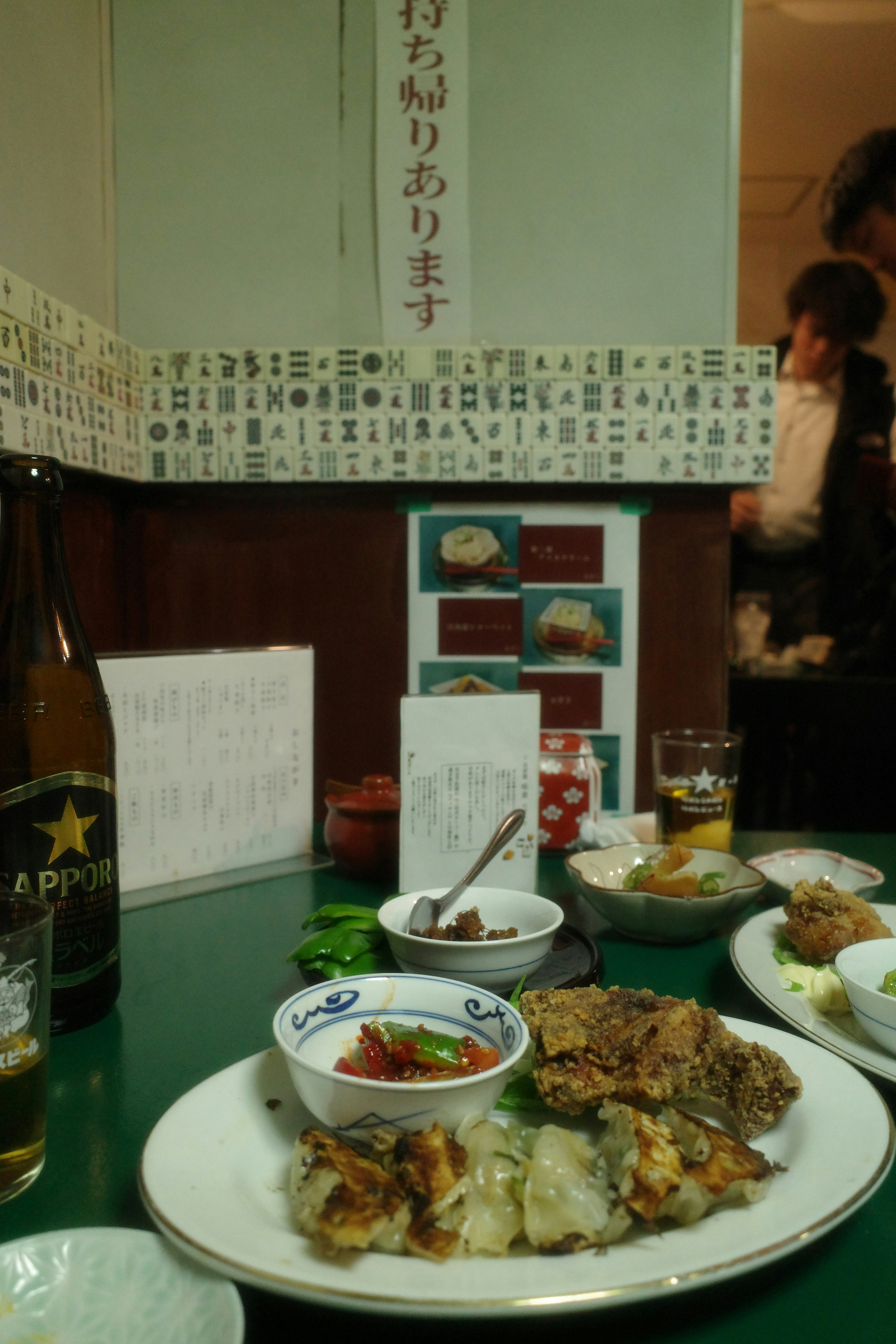 緑のテーブルで並ぶ料理とビールのある店内