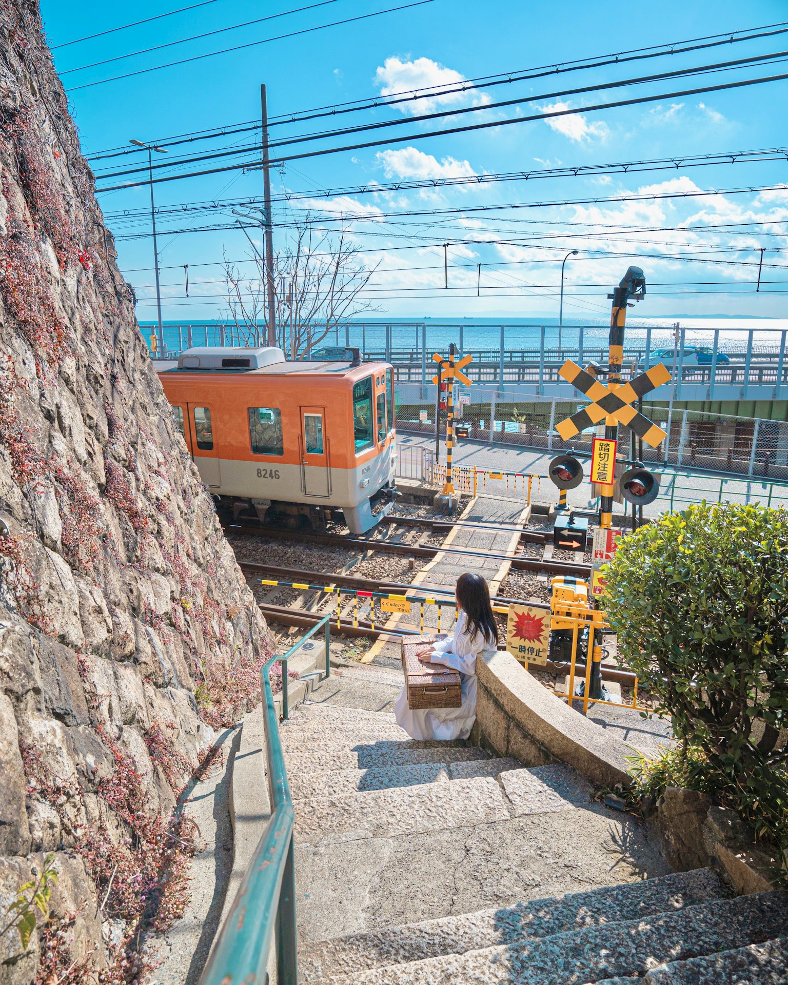 ผู้หญิงที่กำลังลงบันไดพร้อมกับรถไฟสีส้มในพื้นหลัง