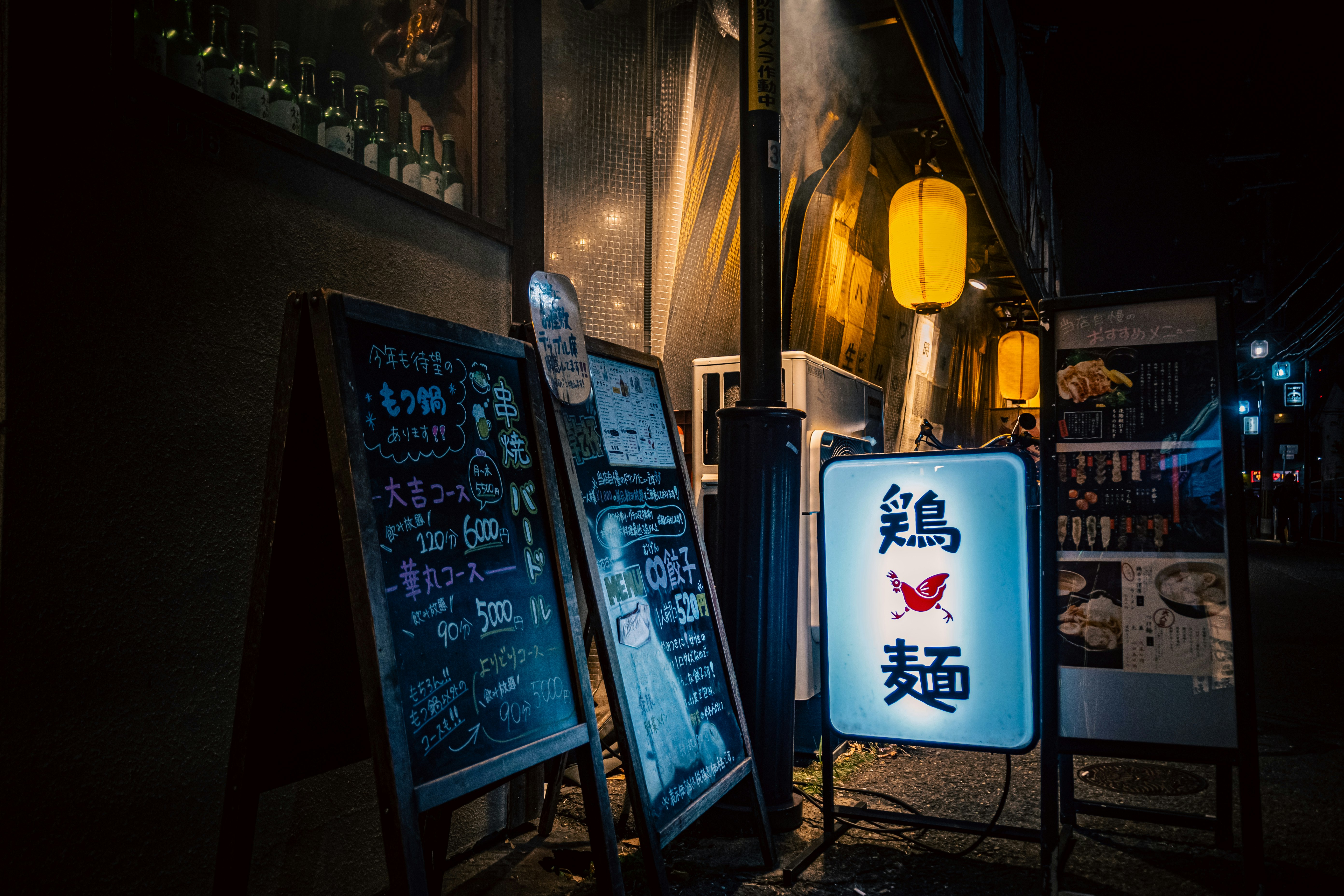 夜の路地に並ぶ看板と提灯のある飲食店の外観