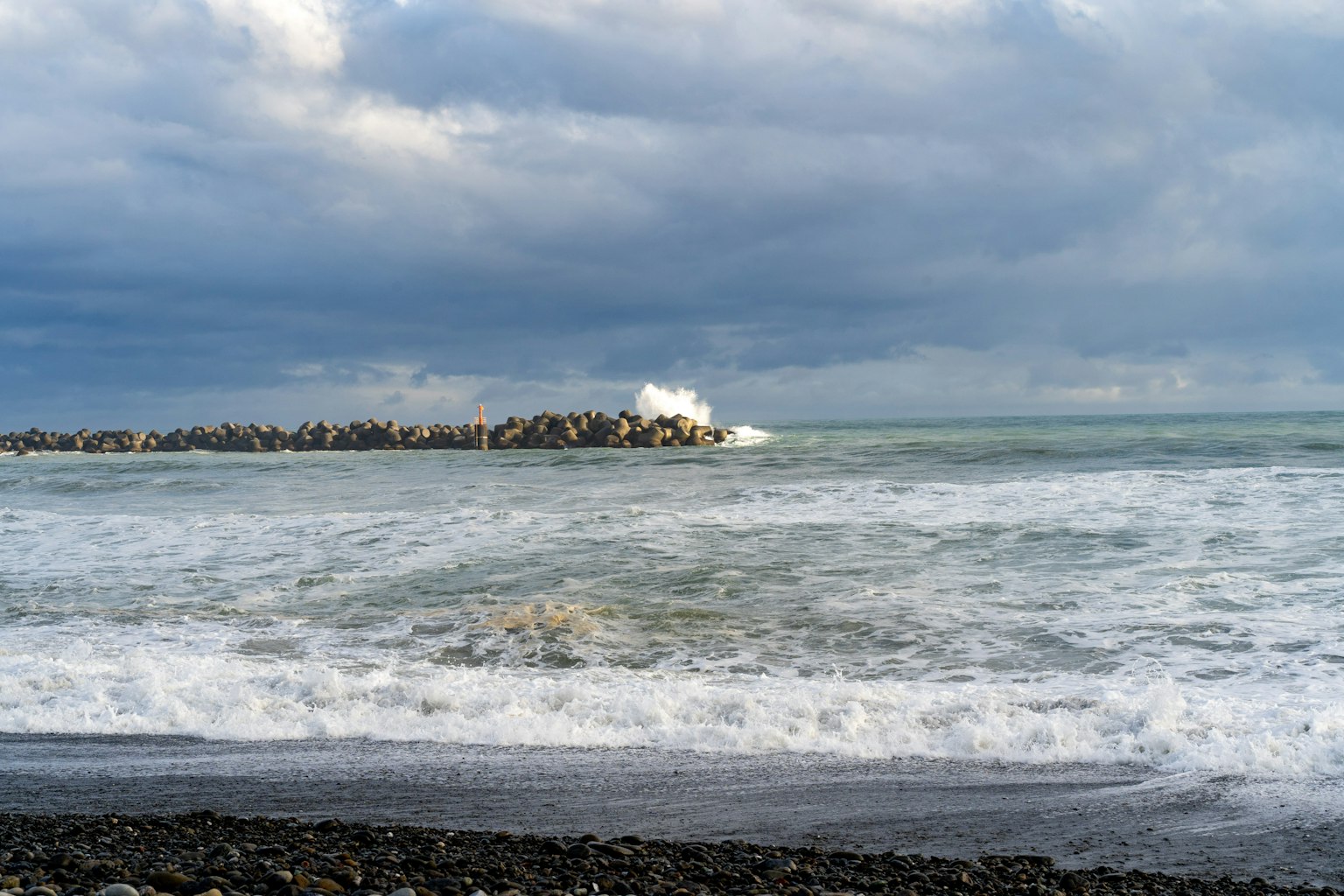 Vue côtière avec des vagues qui s'écrasent et un brise-lame rocheux