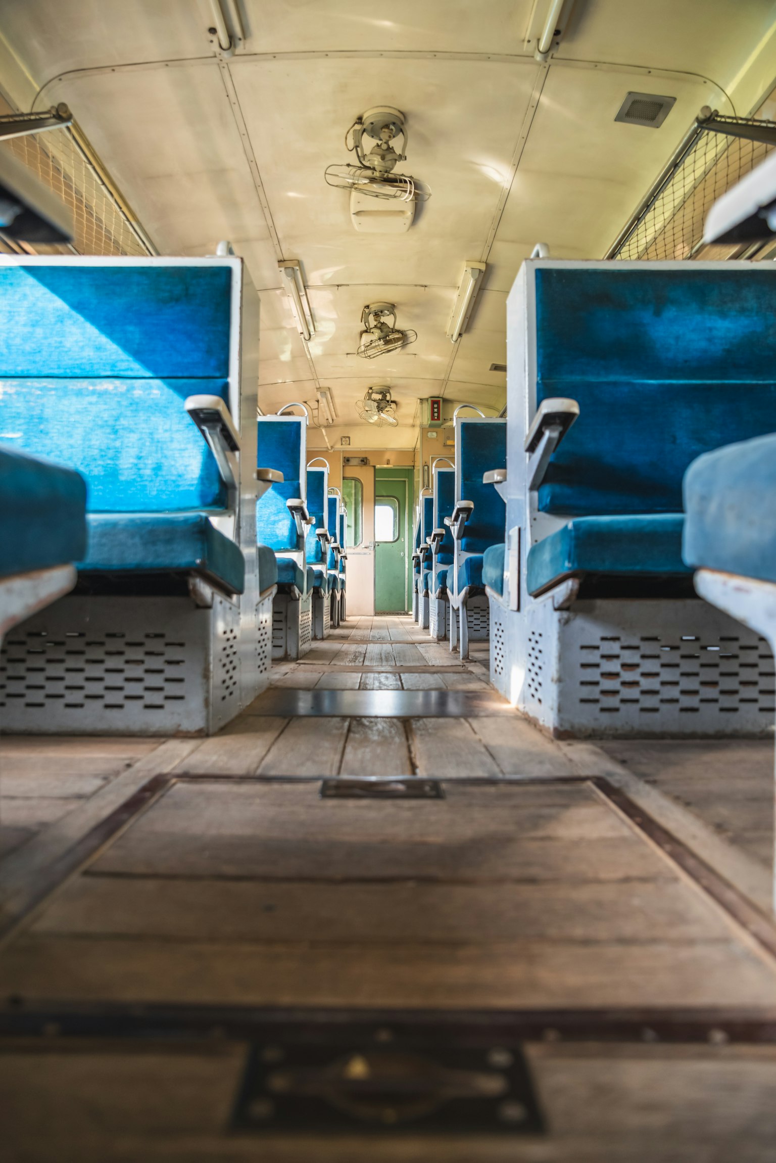 老式火车车厢内部有蓝色座椅和木地板