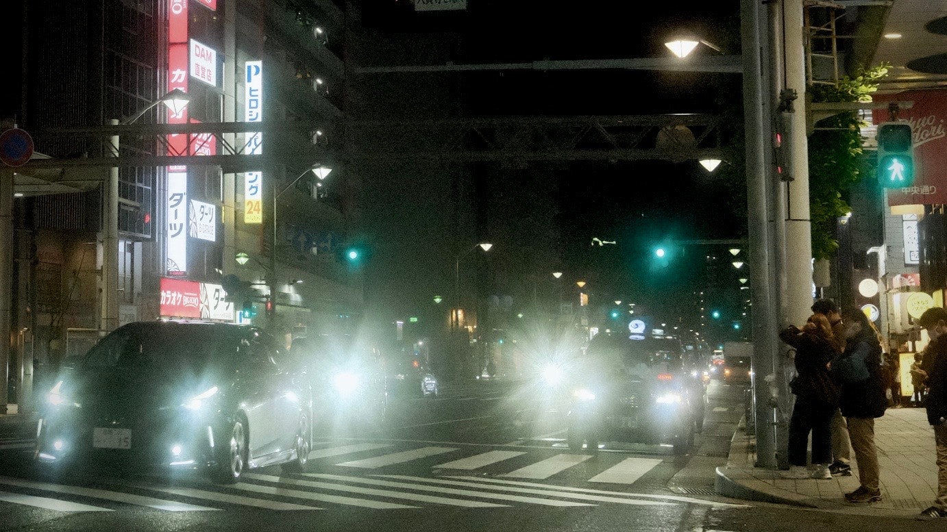 霧のかかった夜の交差点で車のヘッドライトがにじむ