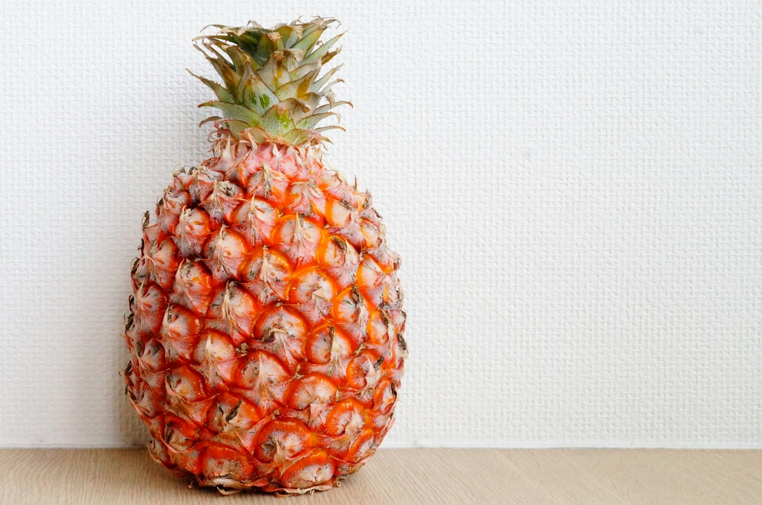 Una piña naranja madura colocada frente a un fondo blanco