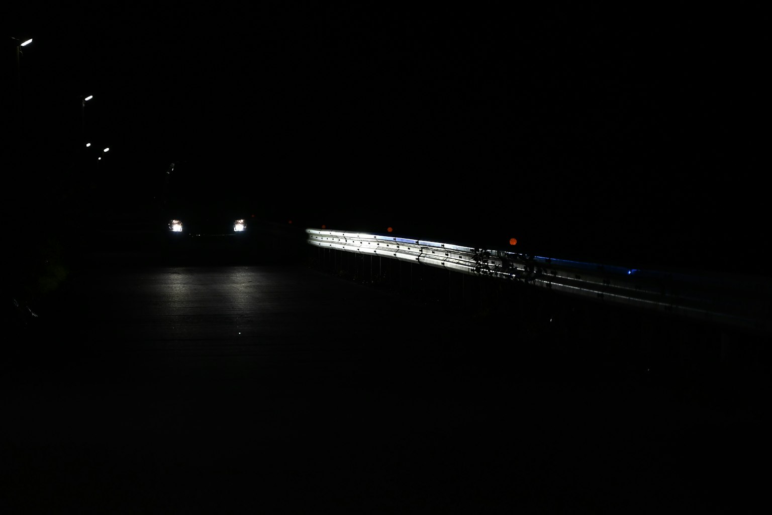 Szene einer dunklen Straße, beleuchtet von Autoleuchten