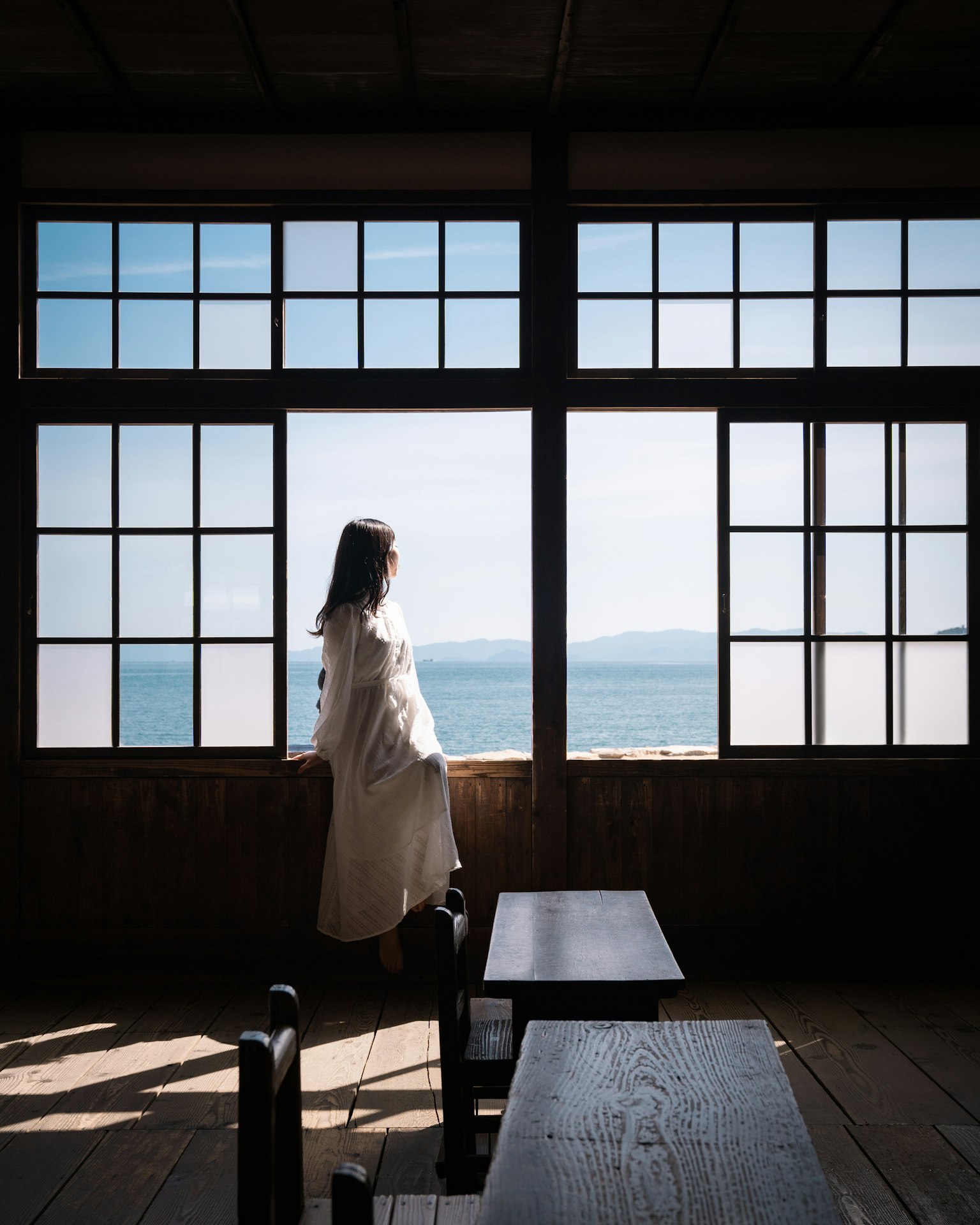 Silhouette di una donna che guarda fuori dalla finestra su una vista mare