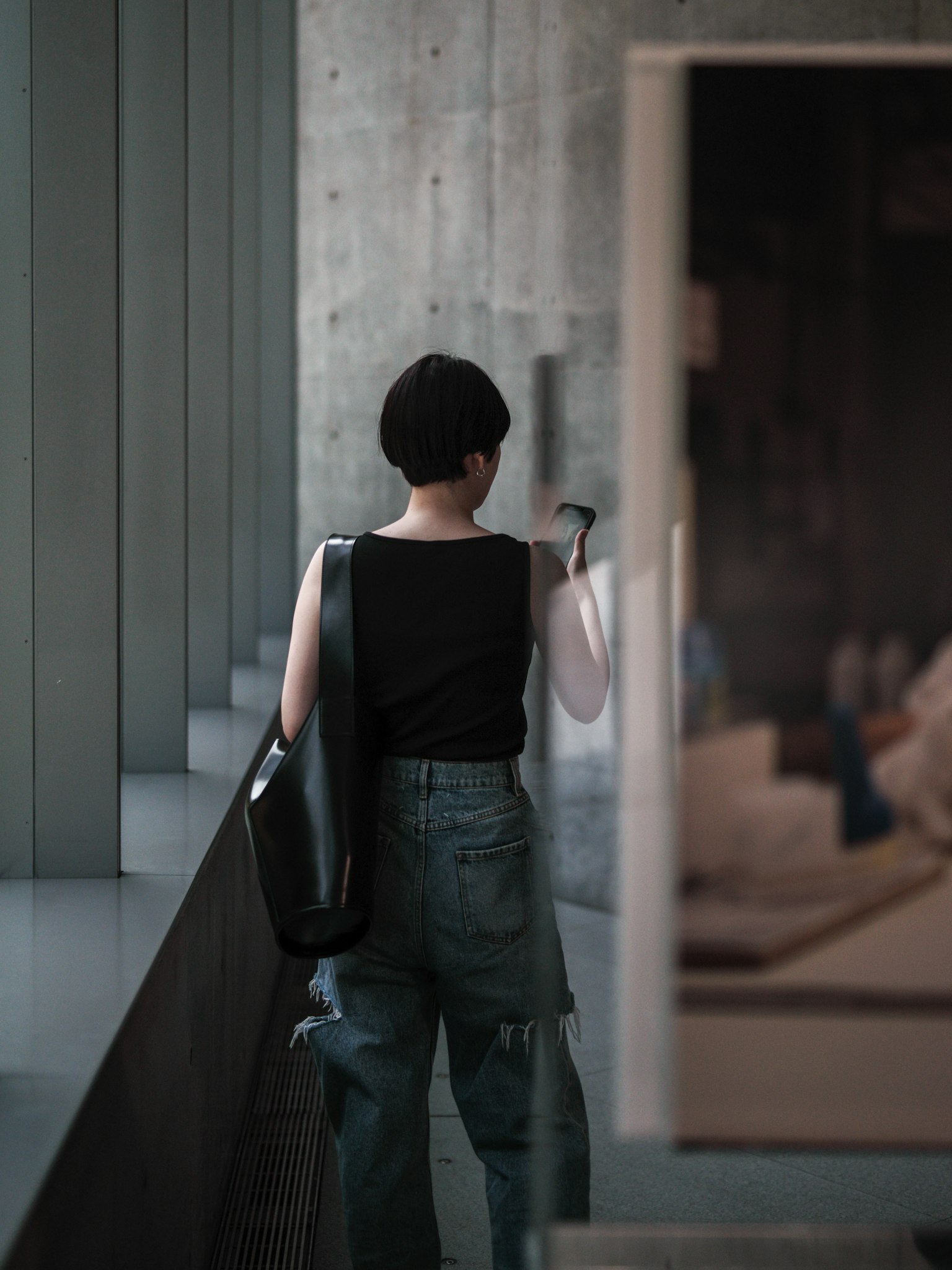 一名女性站在混凝土牆附近,背對著相機