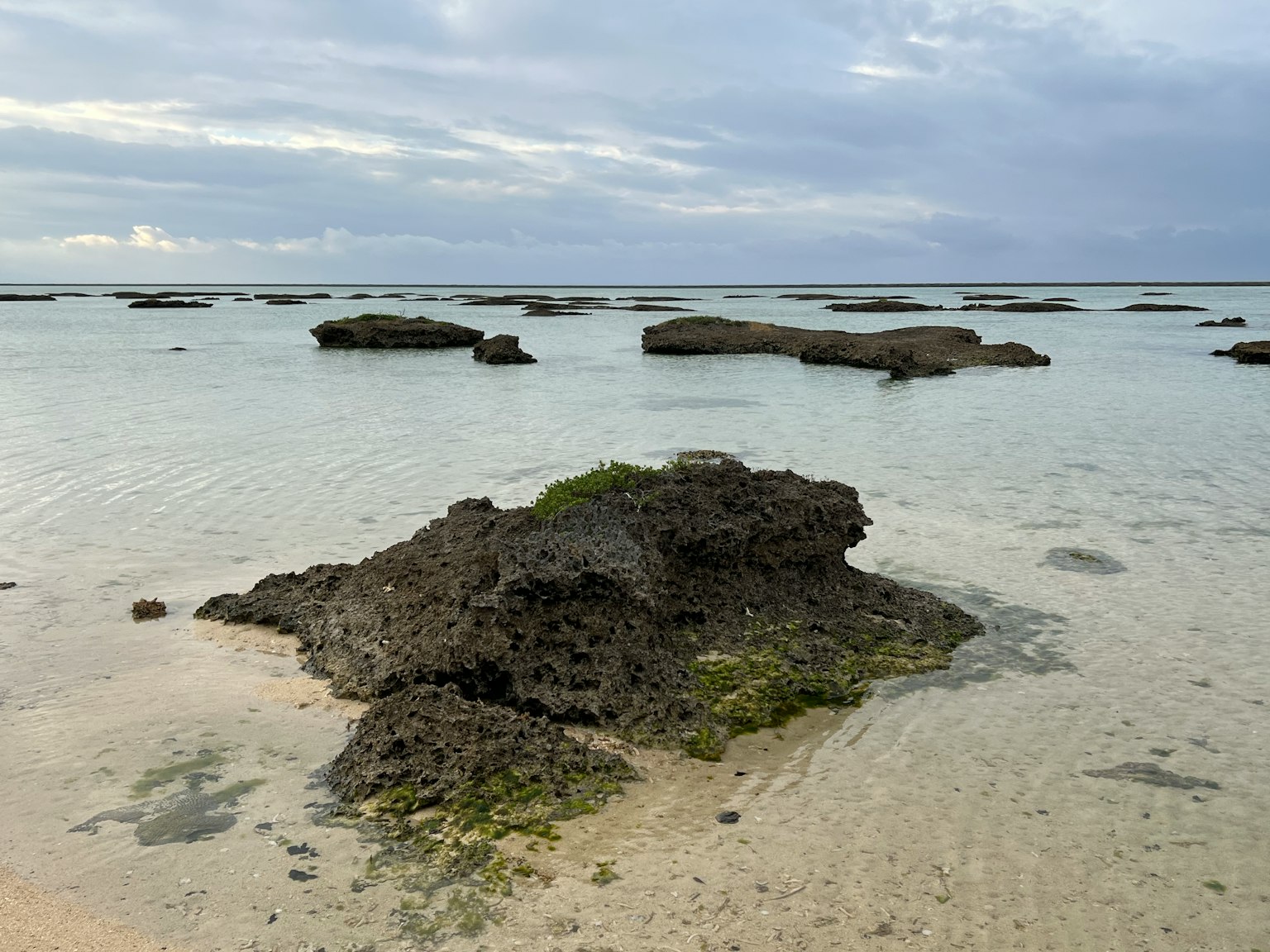 平静的海面上散落着岩石的浅水区和宁静的天空