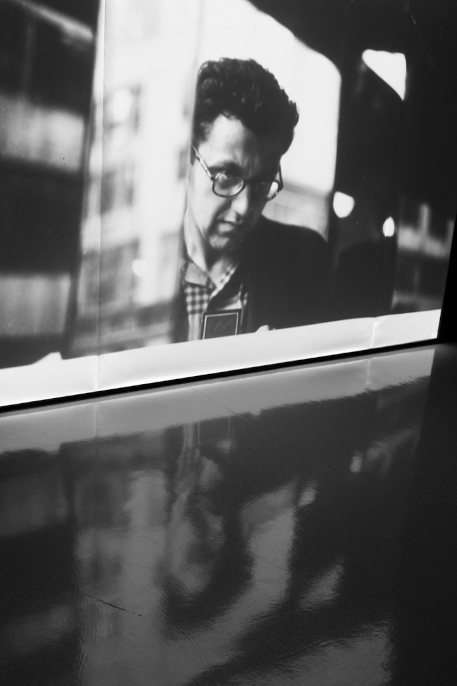 黒と白の写真の中で、男性が集中している姿が映っている 窓越しに外の景色が見える
