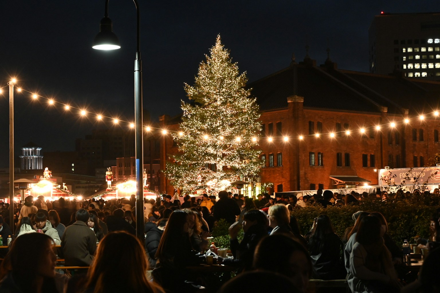 Mercado navideño animado por la noche con un árbol de Navidad brillante