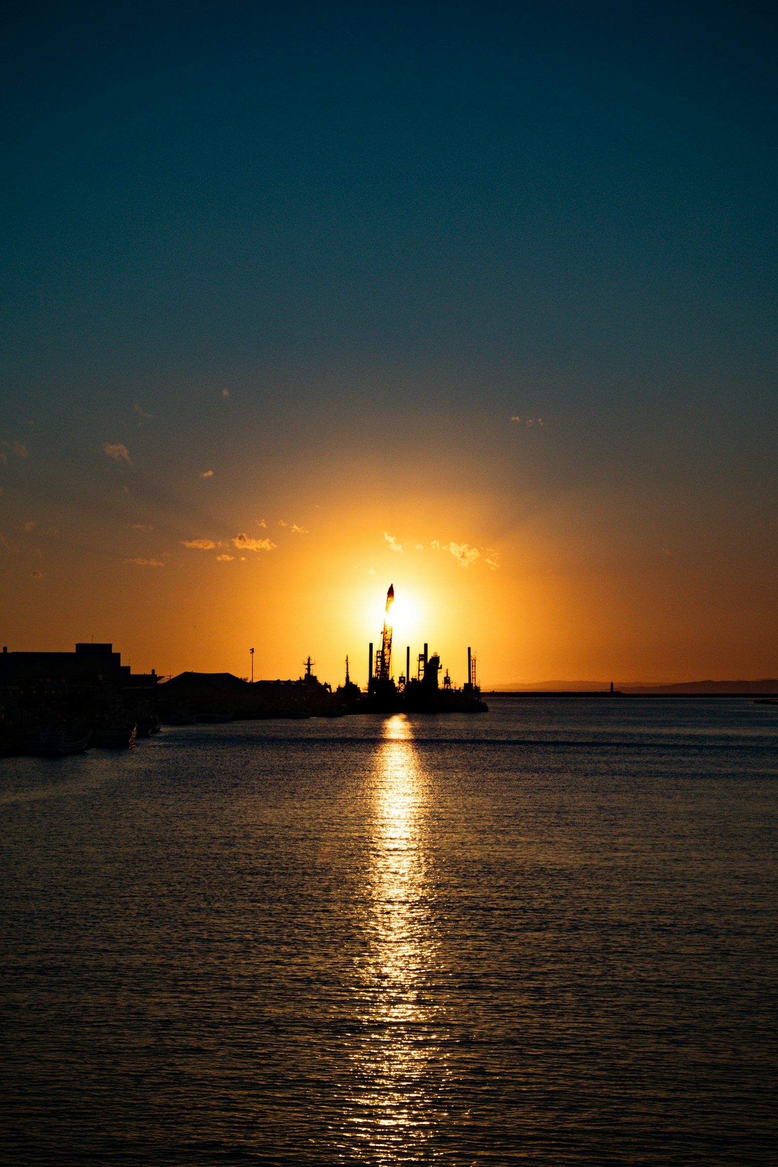 Bellissimo paesaggio con il tramonto che si riflette sull'acqua e la silhouette di una fabbrica sullo sfondo