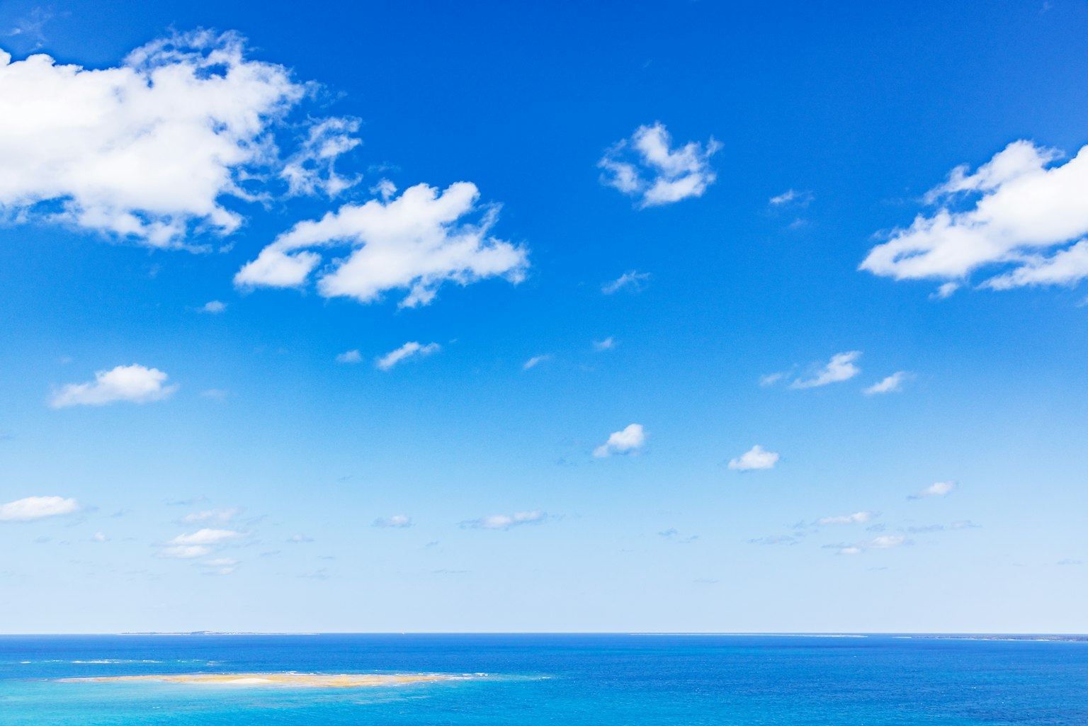 Expansive view of blue sky and ocean with white clouds