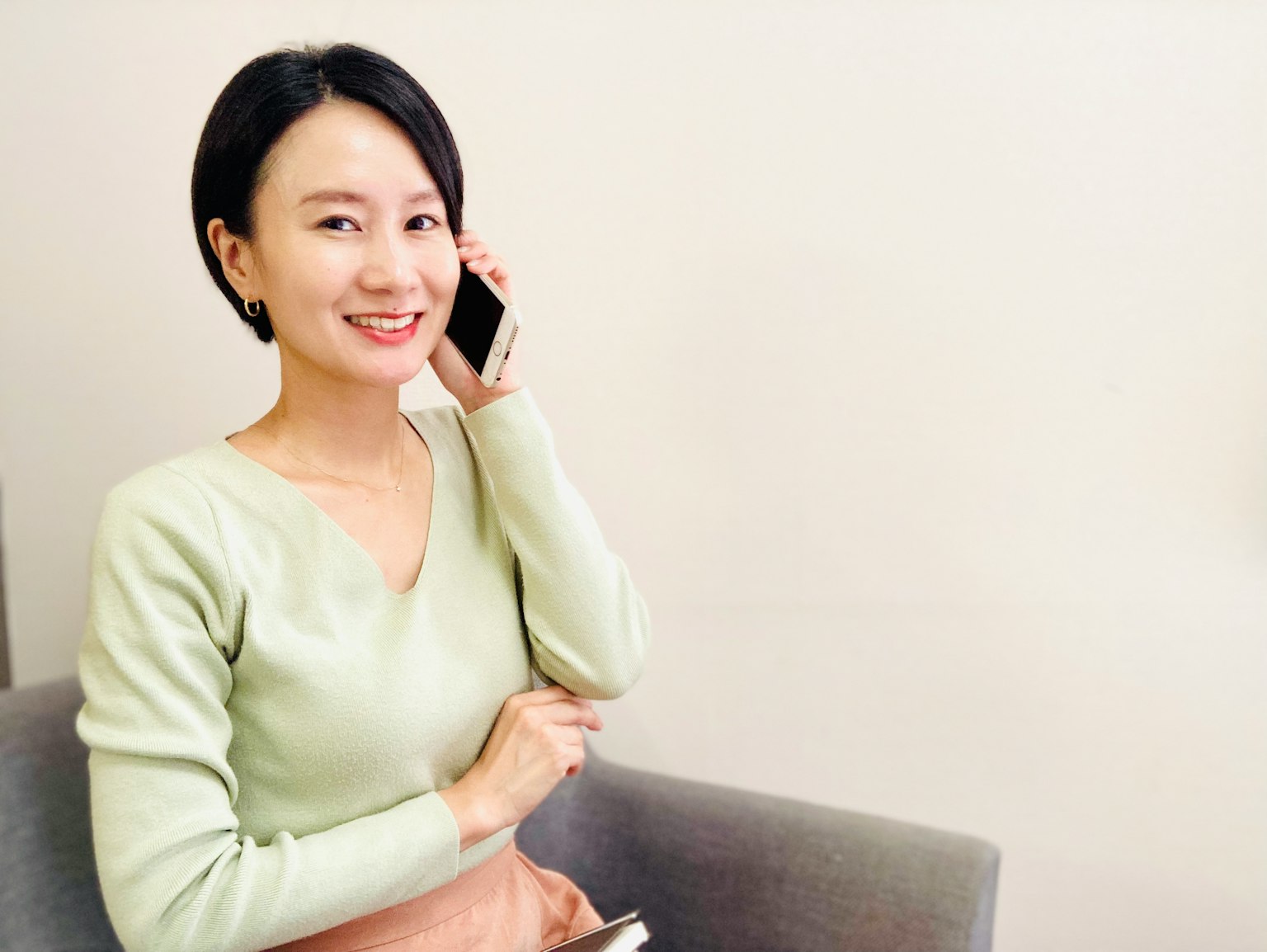 Seorang wanita tersenyum sedang berbicara di telepon